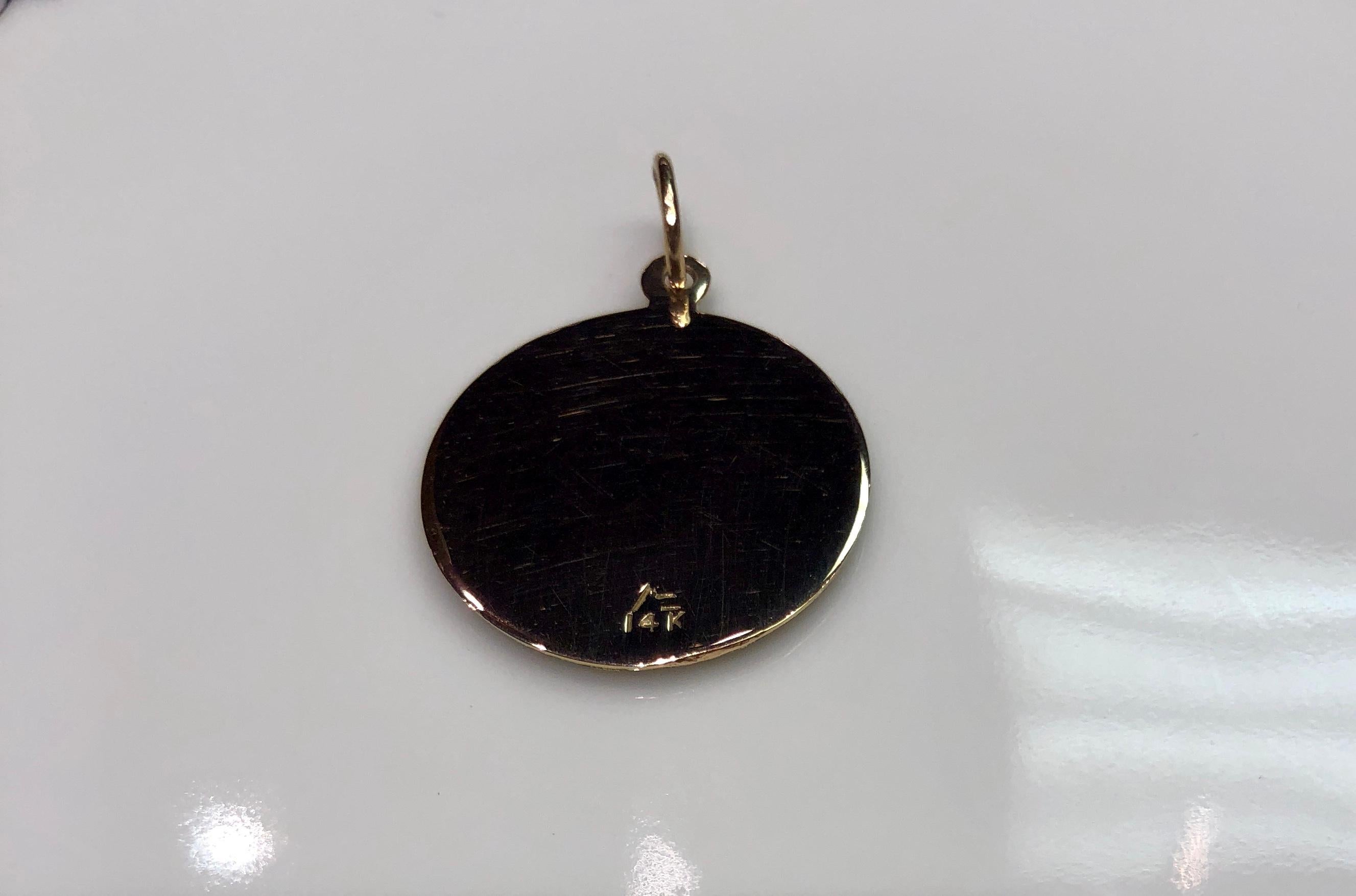 Lovely charm.  14K textured yellow gold.  In the center, an applied white enamel dove in flight above an applied green enamel olive branch.  The branch has gold lettering:   