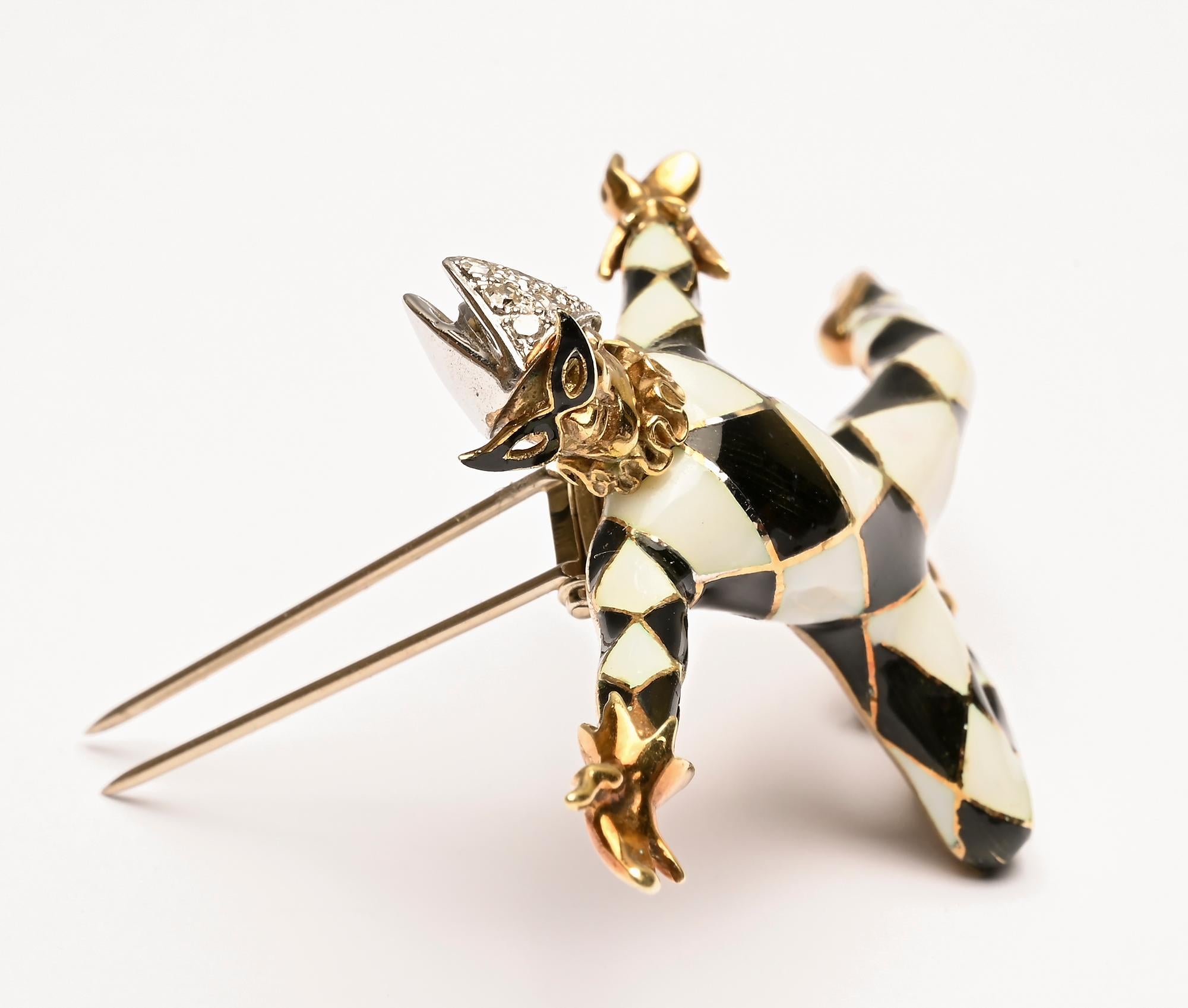 Finely detailed gold jester brooch in which he leaps through the air. The jester is dressed in black and white harlequin clothing with a diamond cap. A ruffled collar and enamel glasses add to the graceful demeanor of this charming acrobat.
He