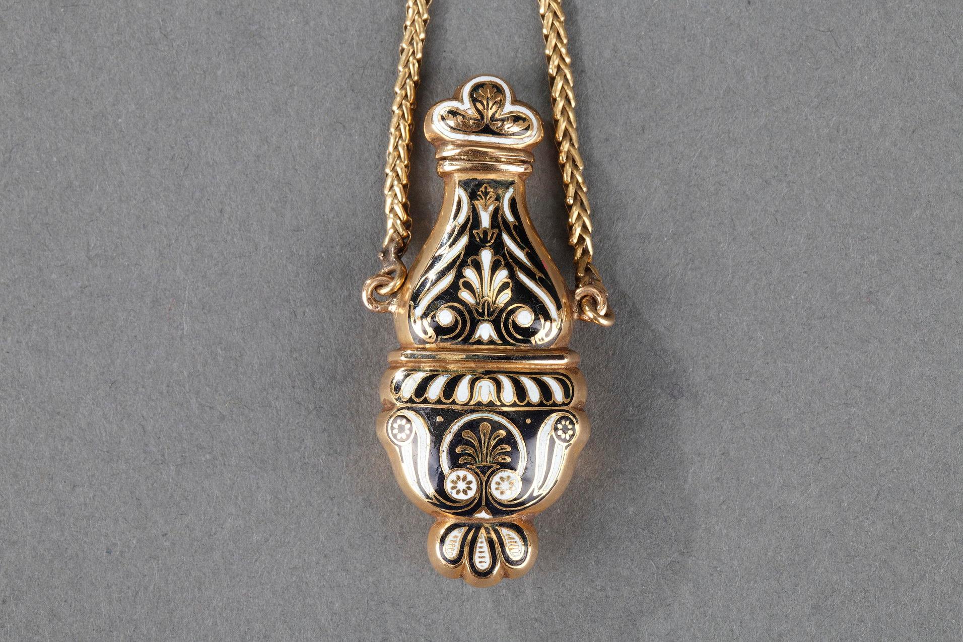 Small perfum bottle in gold and enamel. The flask is decorated with palmettes and foliage motifs in white and black enamel on black enamel background. Two gold chains permitted the suspension of this bottle. The hinged cap opens on a small gold