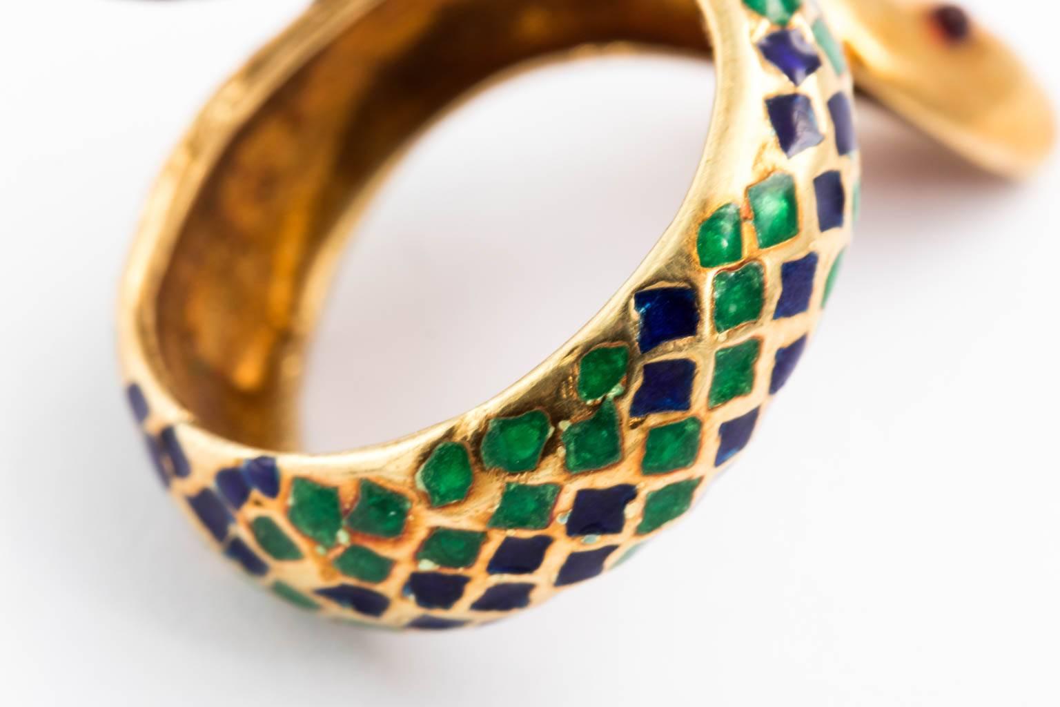 Circa mid 20th century 18 karat solid gold and enamel serpent ring. Scales in green and dark blue with cabochon ruby eyes. Its head and tail are attached so it will not bend.
