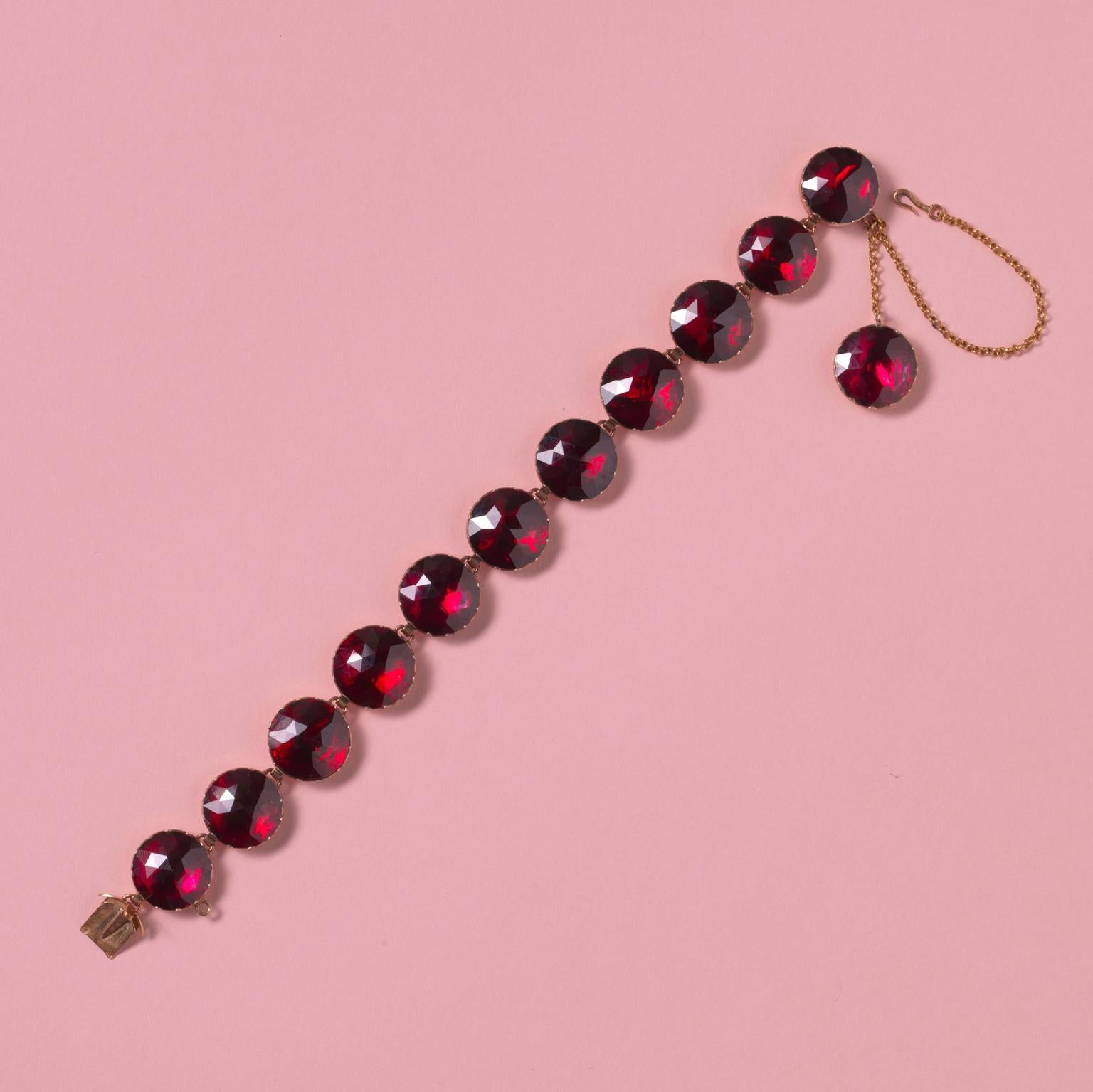 An 18 carat gold important bracelet with 11 large rose cut rhodolite or pyrope garnet links, closed set on red gold foil, an extra link as a charm on the safety chain, 19th century, South of France, Perpignan.

weight: 29 gram
dimensions: 19 x 1.4