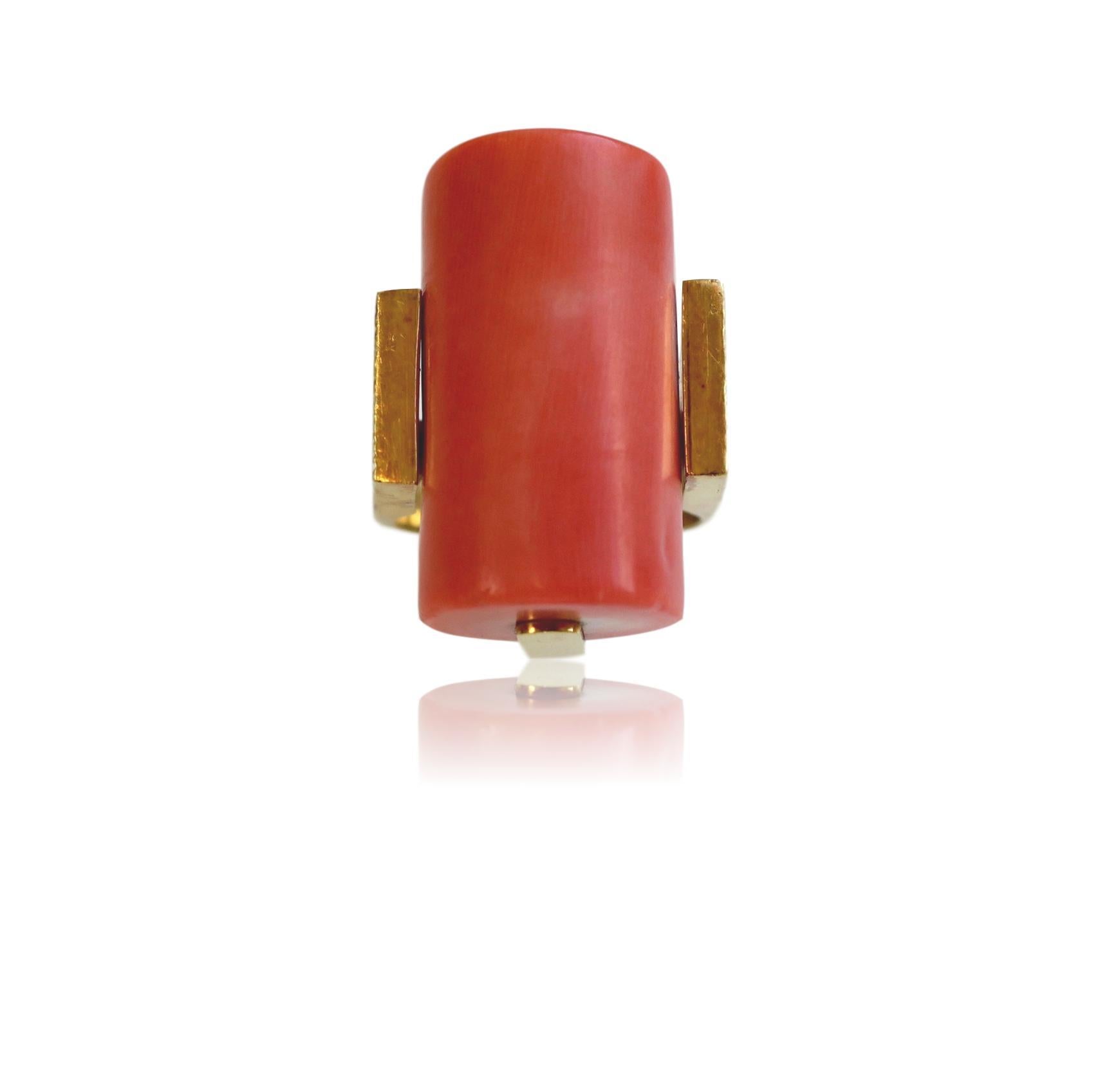 1970's Modernist coral and 18k yellow gold ring. The cylinder-shaped smooth polished coral (just under one inch)  mounted in a wood-grained 18k ring. This coral ring is a very flattering pinkish- orange, the extended shank gives the ring a super