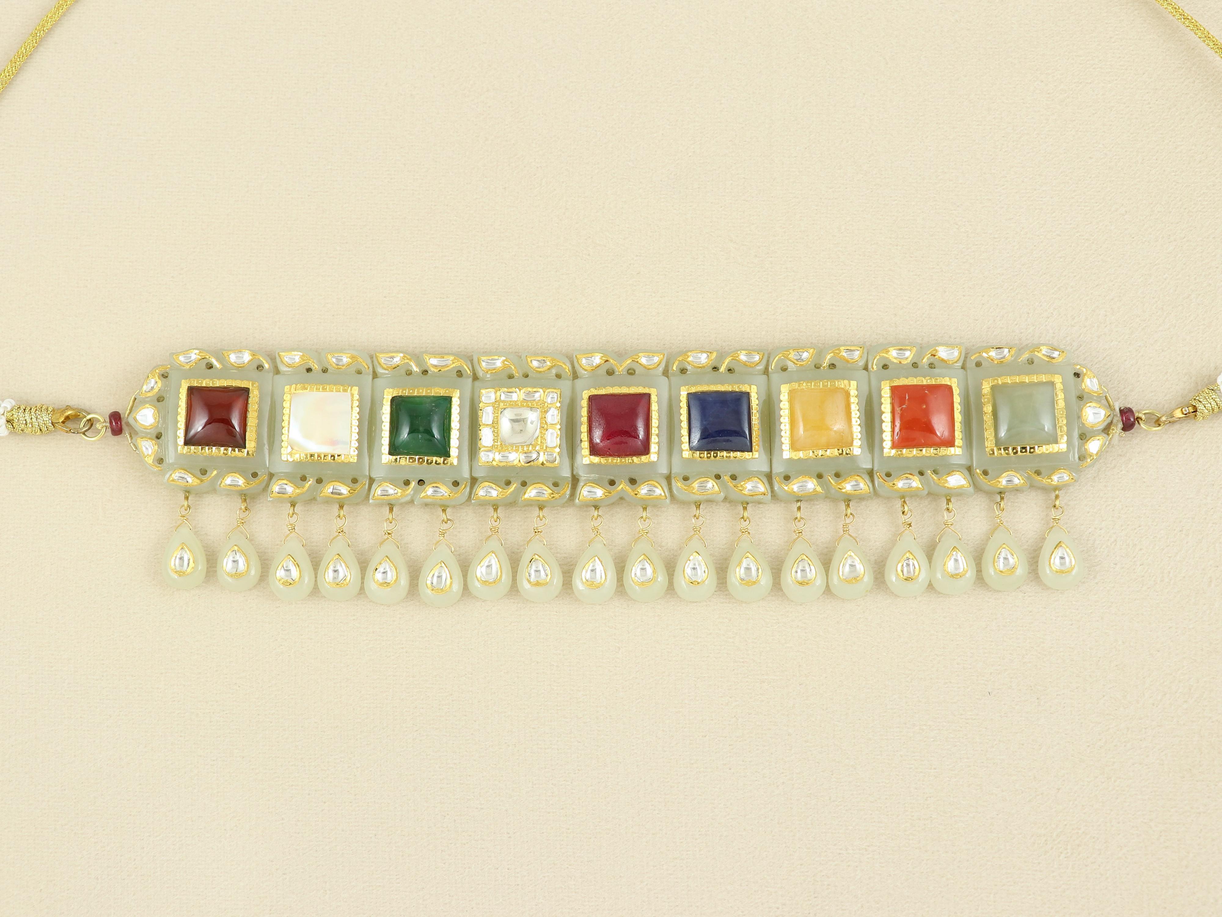 Ethereal and timeless, this Navratna choker necklace is a rare masterpiece crafted from luminous white nephrite jade, revered for its spiritual purity and gentle translucence. Each jade plaque is meticulously hand-carved in traditional Mughal