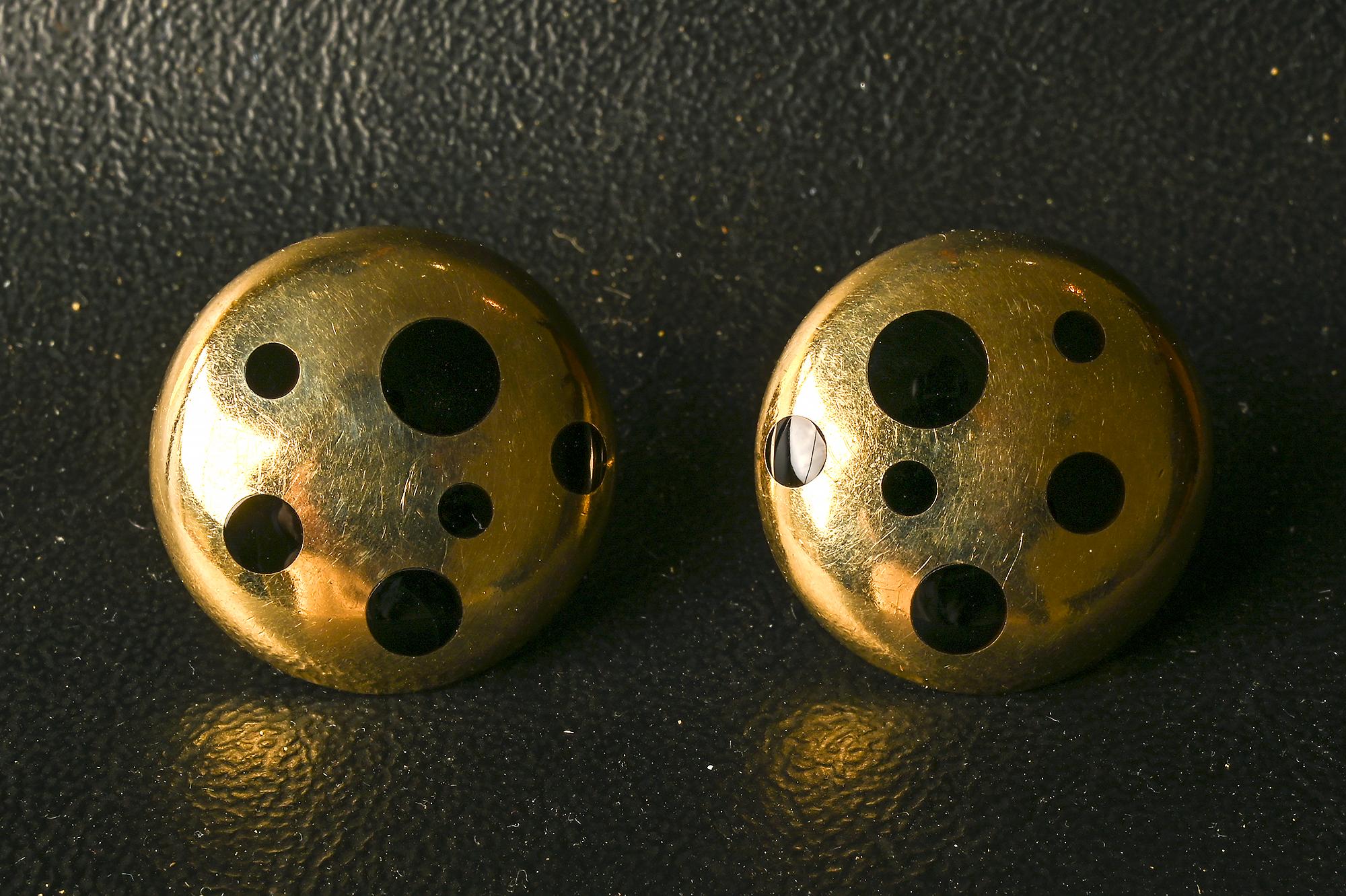 Sporty and sophisticated round gold earrings with inlaid onyx dots of varying sizes. The earrings are one inch in diameter. Backs are clips are posts that can be modified to all one or the other.