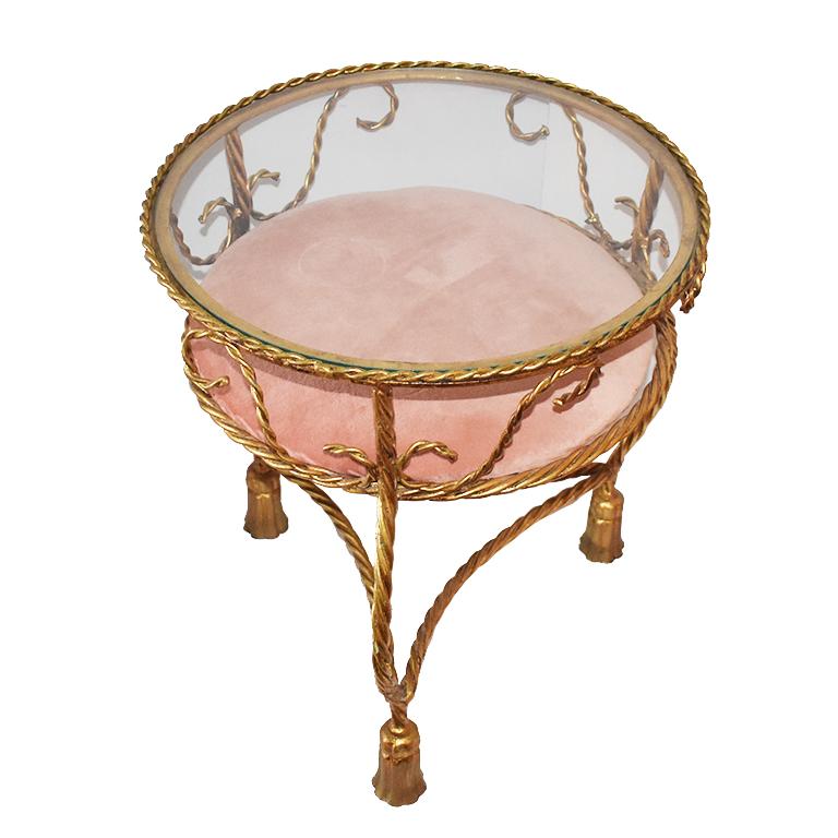 Exceptional Hollywood Regency gilt tole rope and tassel metal occasional table or drink table with glass top and blush pink upholstered cushion. Estimated to be from the 1920s.

This small Trompe L'Oeil occasional table is in gold and reminds us