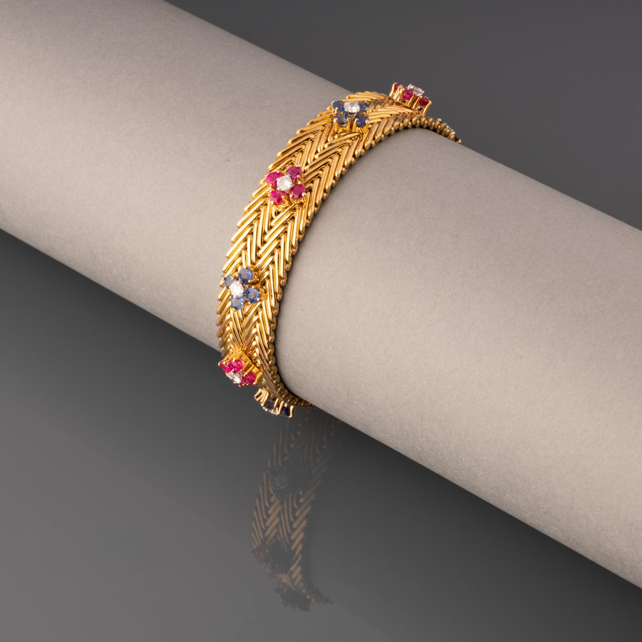 A very beautiful vintage bracelet, made by Régner Paris circa 1955.
Made in yellow gold 18k and set with diamonds, rubies and sapphires. The length is 18cm and width 12mm.

Weight: 47.40 grams