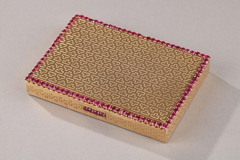 Gold rectangular compact. The lid is engraved with all its faces inverted T lines. The border highlighted with ruby and red stones round faceted claw. The interior opens on a beveled mirror and a compartment closed by a flapper.
The opening is