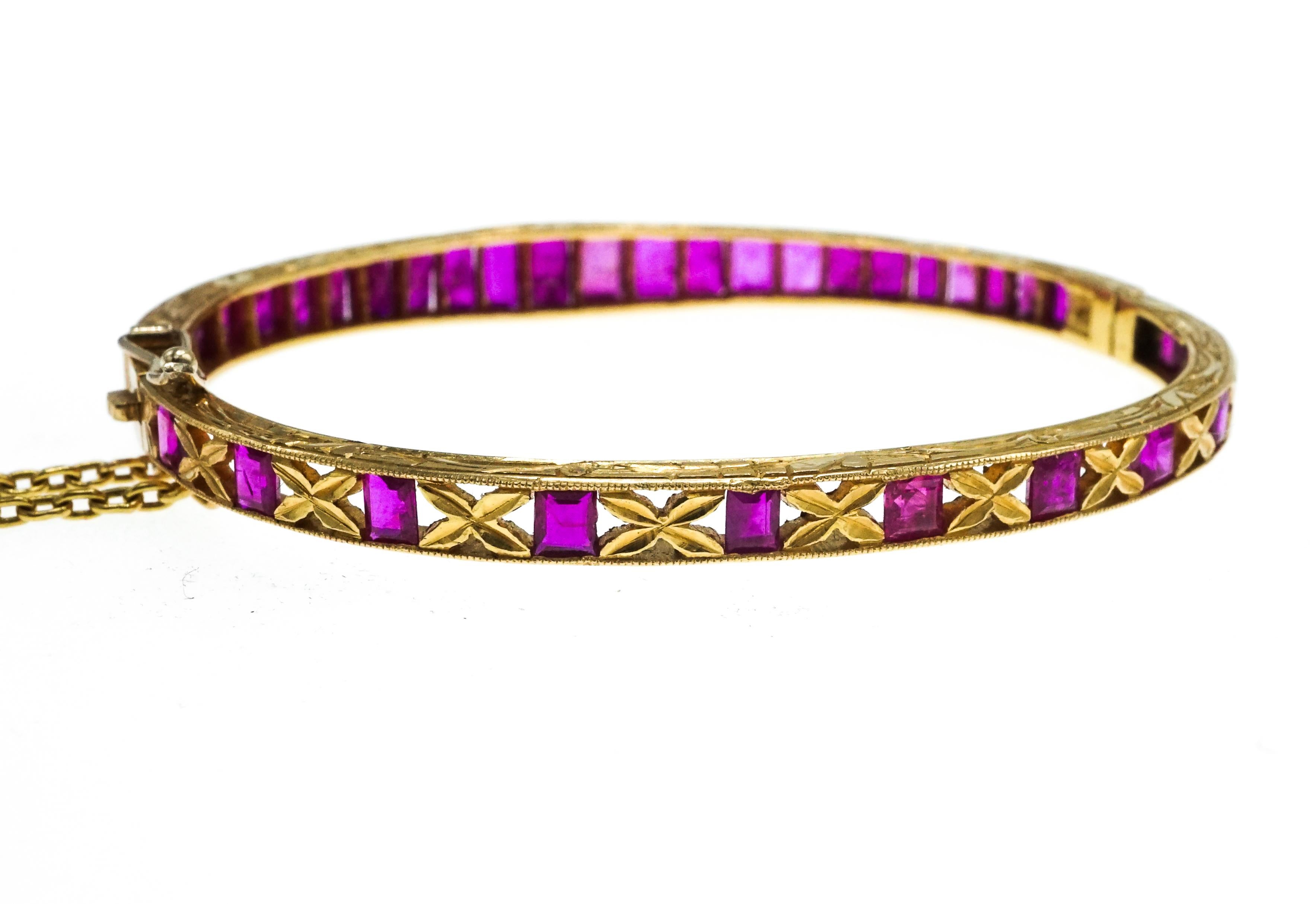 This Gold and Ruby Tapered Bangle Bracelet  features 25 rectangular-cut rubies, the back is set with 11 square-cut rubies spaced by x-shaped petals, altogether approximately 9.50 cts., with floral chased sides, approximately 10.7 dwts. Inner circle