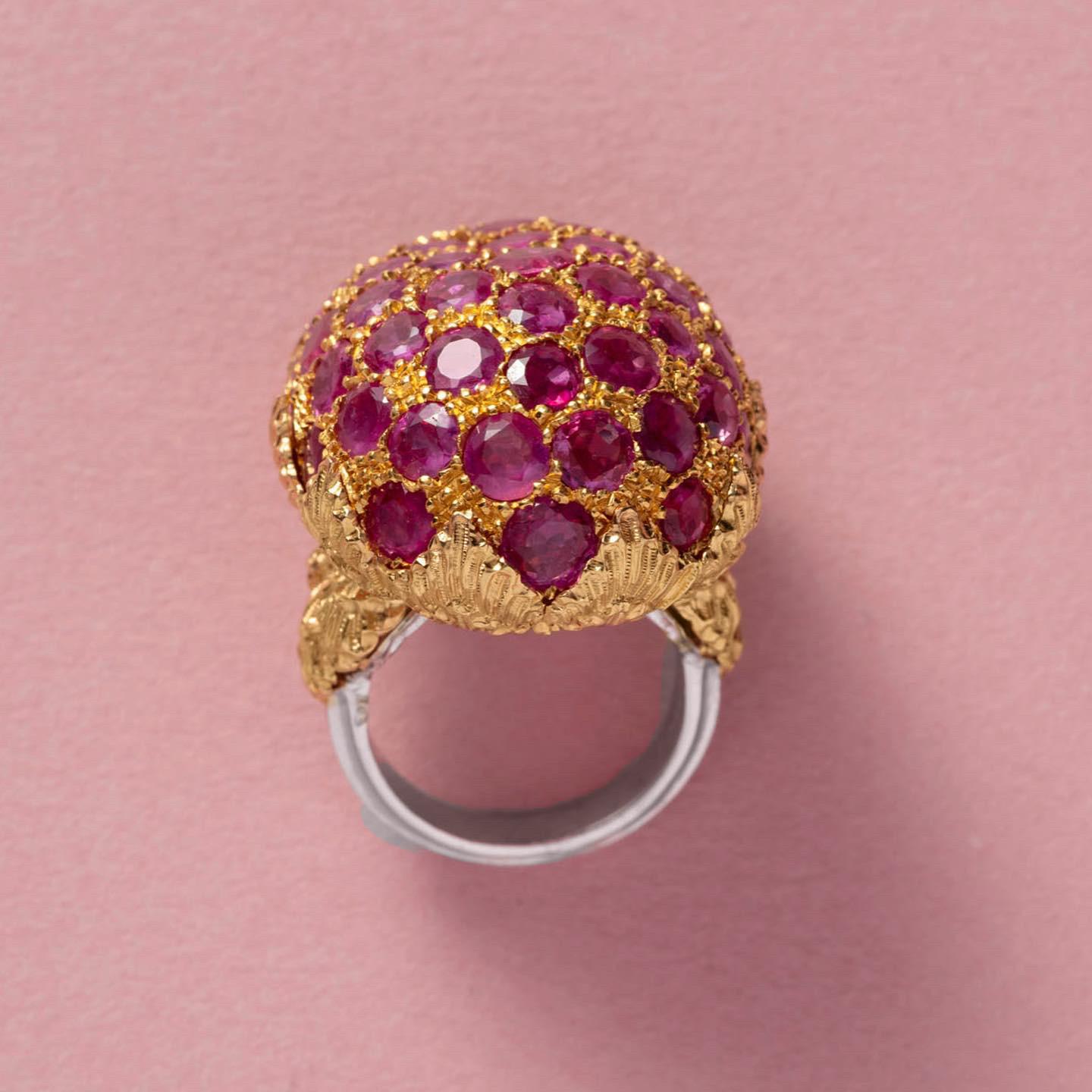 A tri-color 18 carat gold ring with a large ball irregularly set with rubies held by a rosé gold florally decorated mount on a white gold shank, signed Gianmaria Buccellati, with the master mark 763 mi for Gianmaria Buccellati, Italy, circa