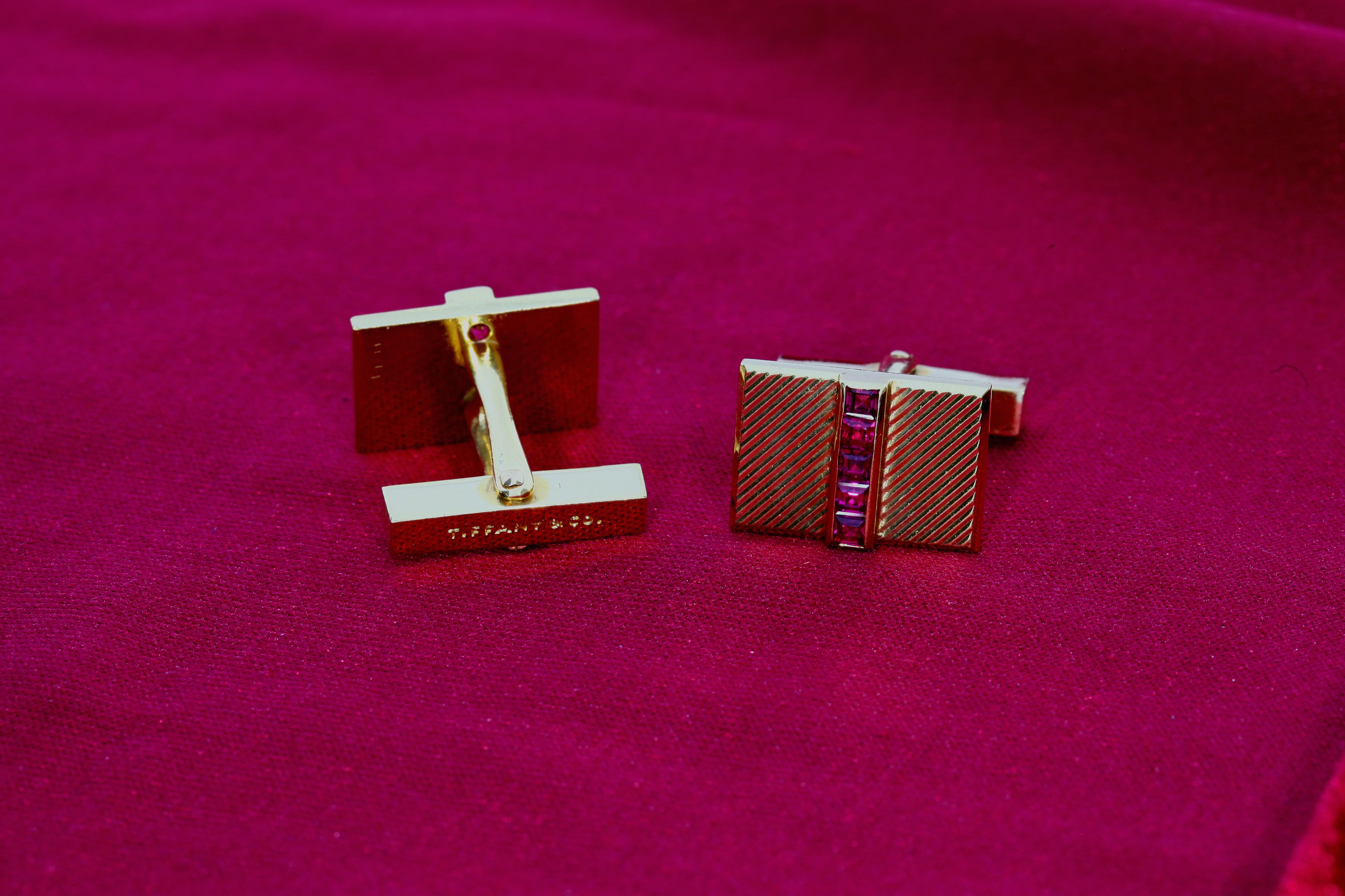 These Tiffany & Co cufflinks feature a diagonally stripped pattern and have a central line of five square cut rubies down the middle in each. 18 Karat yellow gold. 