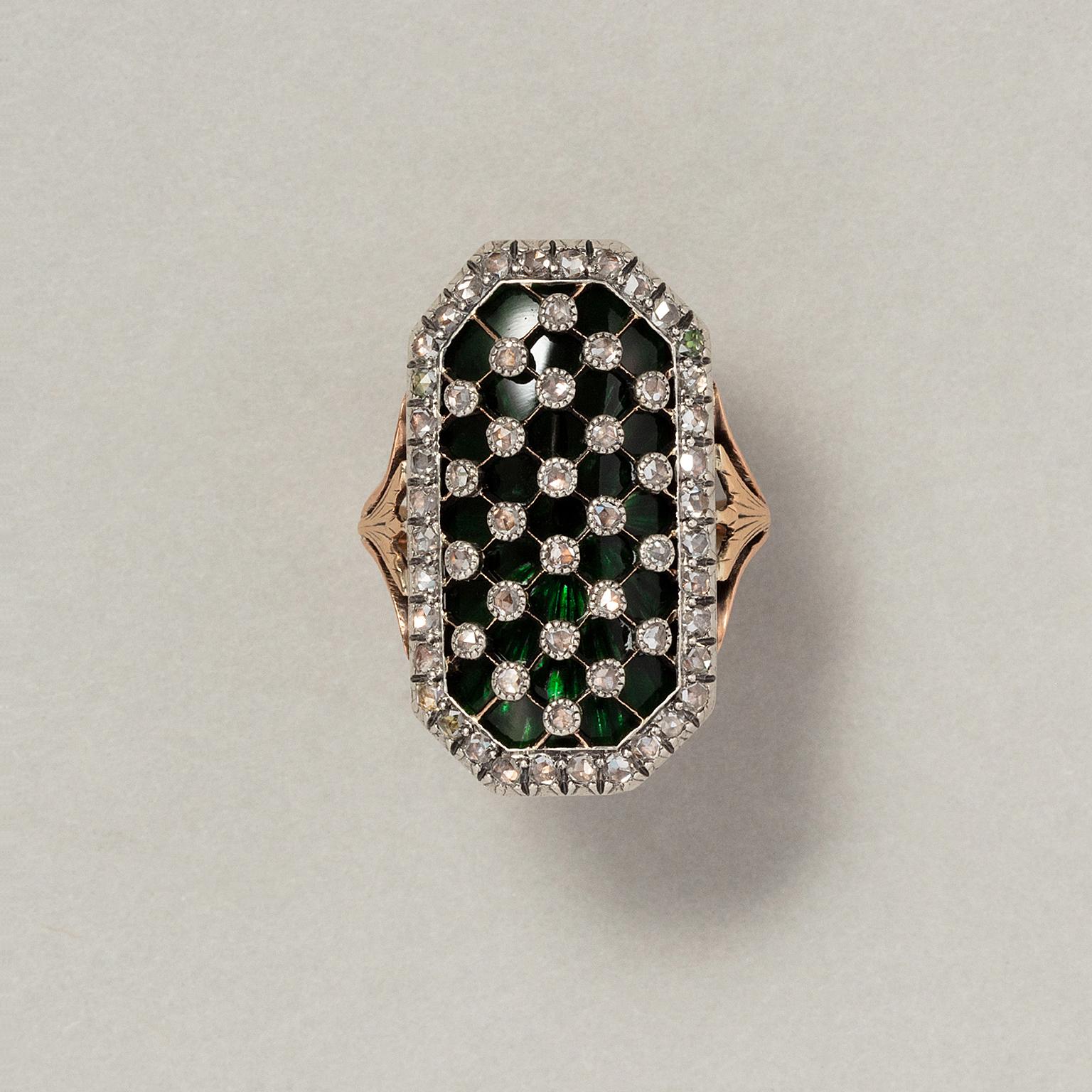 An extraordinairy 18 carat gold and silver bague au firmament with an octagonal convex element with a translucent dark green glass panel over which a silver diagonal grid set with rose cut diamonds, with a five forked hoop with lotus flowers,