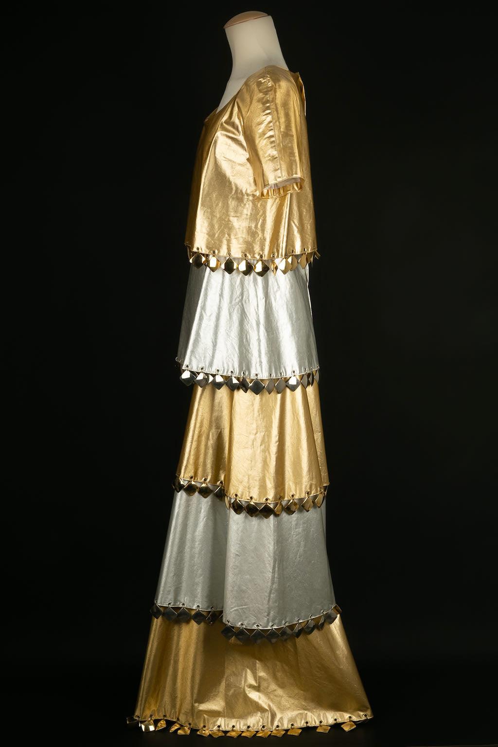 Paco Rabanne -Longue robe en toile enduite argentée et dorée agrémentée de plaques métalliques dorées. Pas de Label de taille ou de composition, il convient à une taille 36FR.

Informations complémentaires : 

Dimensions : 
Largeur des épaules :