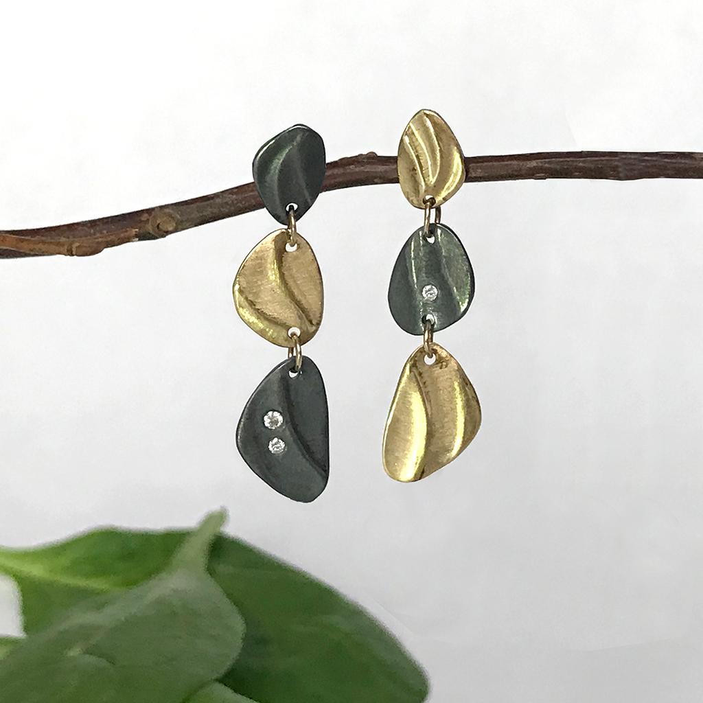 K.Mita's modern Mini Pebble Dangle Earrings are handmade by the artist from 14 Karat Yellow Gold and Oxidized Sterling Silver. The contemporary earrings, which are 31 mm long and 8 mm wide, are accented with three Diamonds (0.03 Carats total weight)