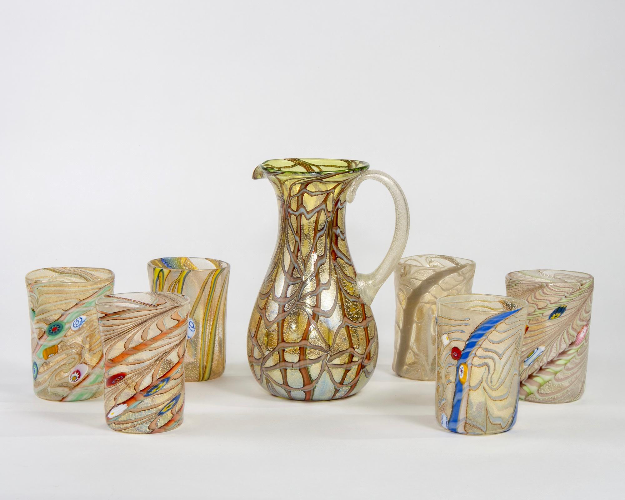 Contemporary set of handcrafted Murano glass pitcher and six coordinating glasses. Pitcher is made of gold and silvery glass with amber and brown accents; glasses have silver, white, gold, brown, red and blue accents. Makes a beautiful gift for a