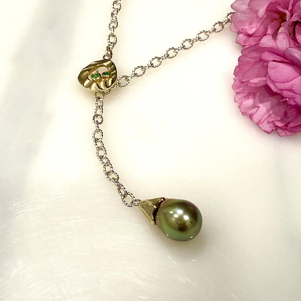 Keiko Mita's modern Pearl Lariat Necklace from her Sand Dune Collection is handmade from 14 Karat Yellow Gold and features the artist's signature movement and Dune texture. A beautiful light golden green Tahitian Pearl and Green Garnet accents (0.85