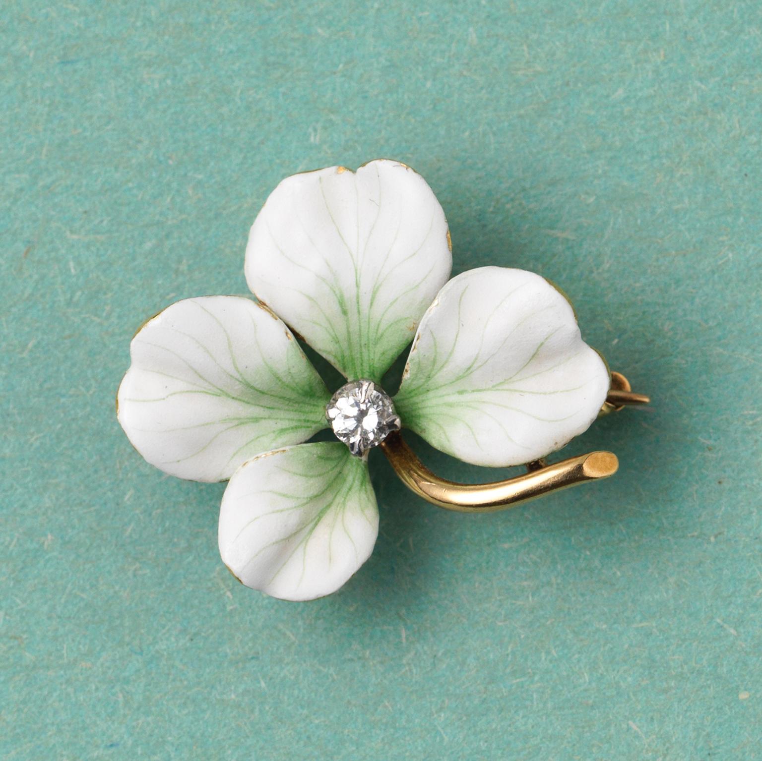 A 14-carat gold brooch in the shape of a white flower or four-leaf clover decorated with white and green enamel and an old-cut diamond in the heart of the flower (app. 0.15 carat), master’s mark HB, possibly for early Oscar Heyman & Brothers. USA,