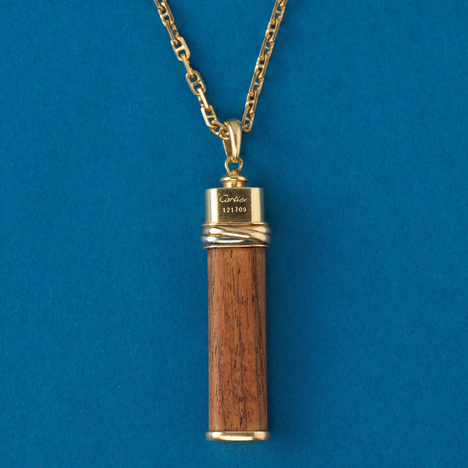 An 18 carat gold lucky “touch wood” or “toucher du bois” Cartier Trinity pendant. A long piece of wood with a tri-color gold band and an oval hoop, signed and numbered: Cartier 121709, circa 1980.

weight: 7.39 gram.
dimensions: 5.8 x 1.2 cm.
