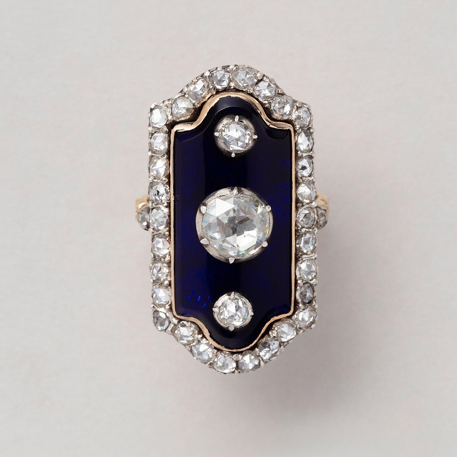 A 14 carat gold ‘au Firmament’ ring set with an octagonal blue glass panel the bottom and top are cuvred like a clock gable set with three central cushion cut diamonds, the center stone larger (0.75 ct.) with a border of rose cut diamonds, European,
