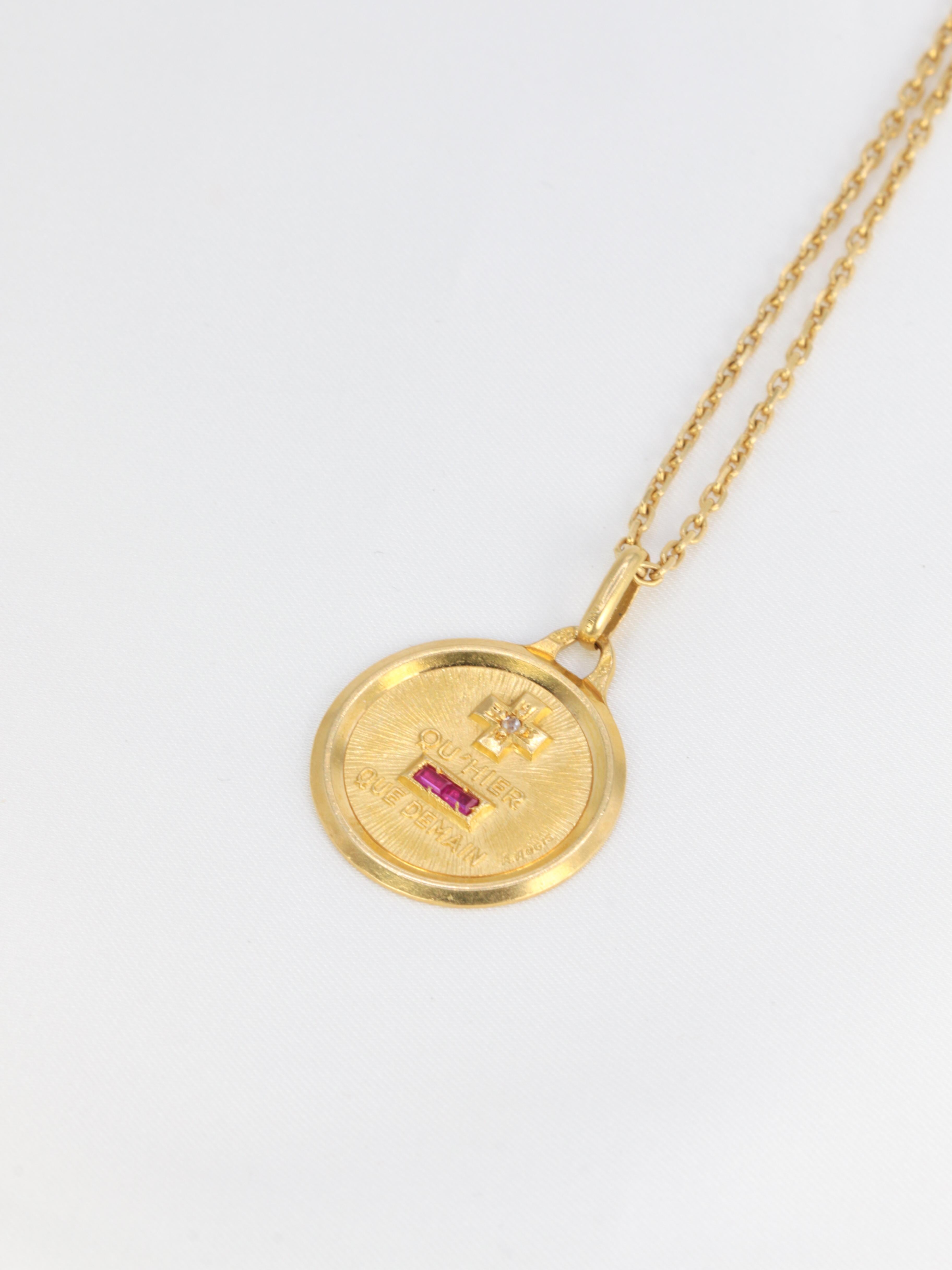 18Kt (750°/°°) gold Augis love medal set with baguette-cut synthetic rubies and a small rose-cut diamond.
The famous sentence Plus qu'hier Moins que demain, inspired by two verses by Rosemonde Gérard Rostand, is written on the medal.
French work