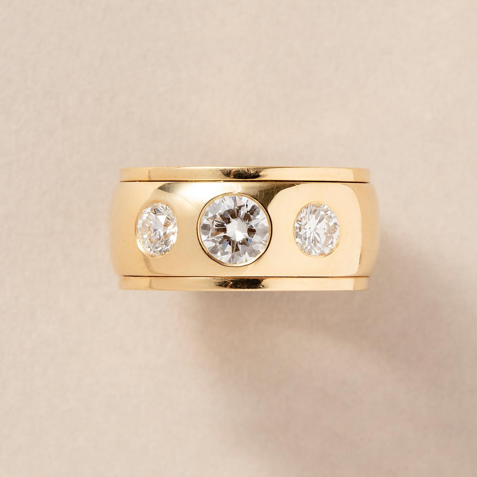 Anello a fascia in oro 18 carati con tre diamanti taglio brillante (0,9 carati H-Vs2 e ai lati 0,51 H-Si1 e 0,50 H-Si1).

peso: 32,3 g
Misura dell'anello: 17 mm / 6,5 US
larghezza: 1,2 cm
