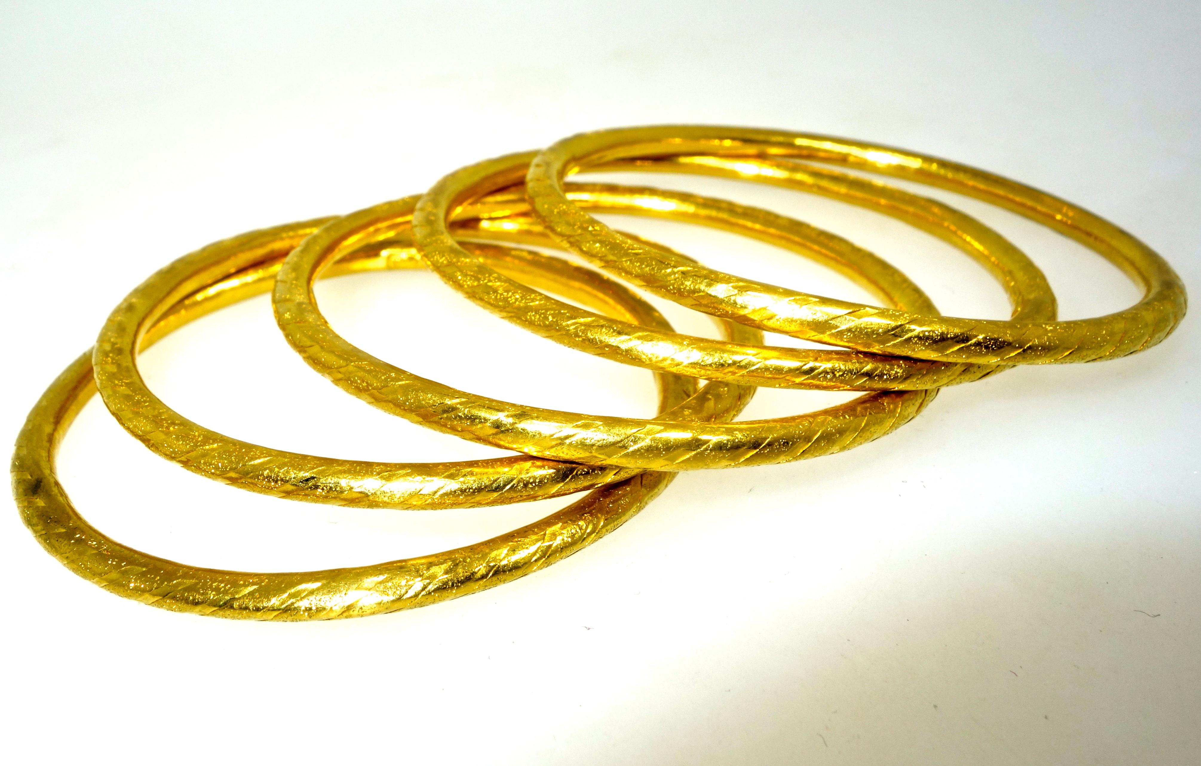 Gold bangle bracelets, 5 in number, and a high karat content, .965 pure.  These slip on bracelets have an interior circumference of 6.8 inches, they weigh 75.5 grams.  They, overall are in fine condition, however if one looks carefully there are 4