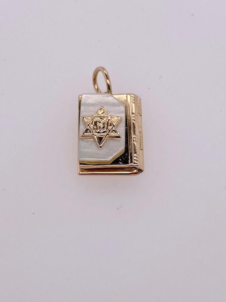 Gold Bible charm.  14K yellow gold.  The front is an inset plaque of mother-of-pearl, with an applied Star of David.  Inside are scrolls with Hebrew prayers.  1/2