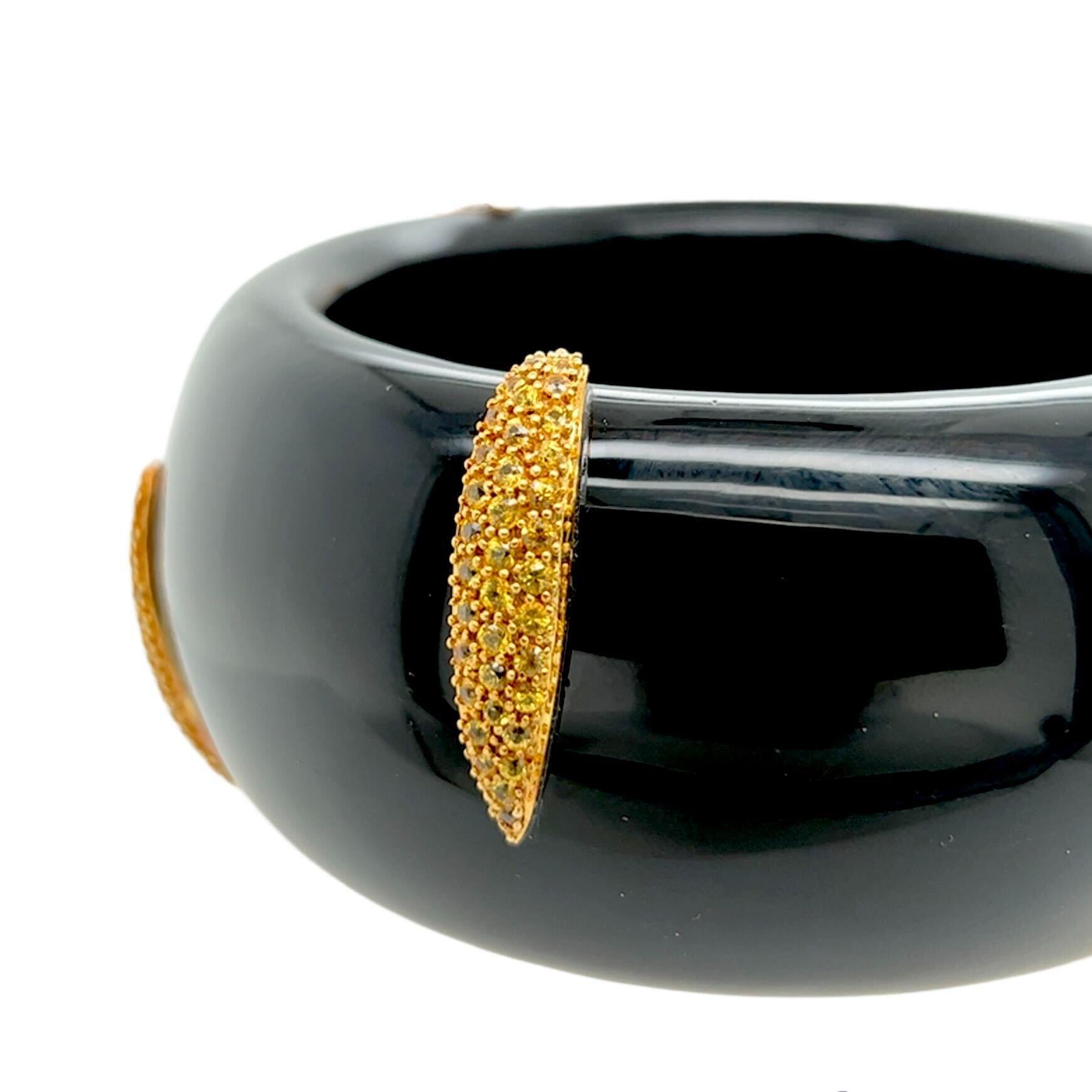 An 18 karat yellow gold, black onyx and yellow diamond bracelet.  Designed as a bombe bangle of carved black onyx applied with six gold navettes set with approximately two hundred ten brilliant cut fancy yellow diamonds.  Total diamond weight