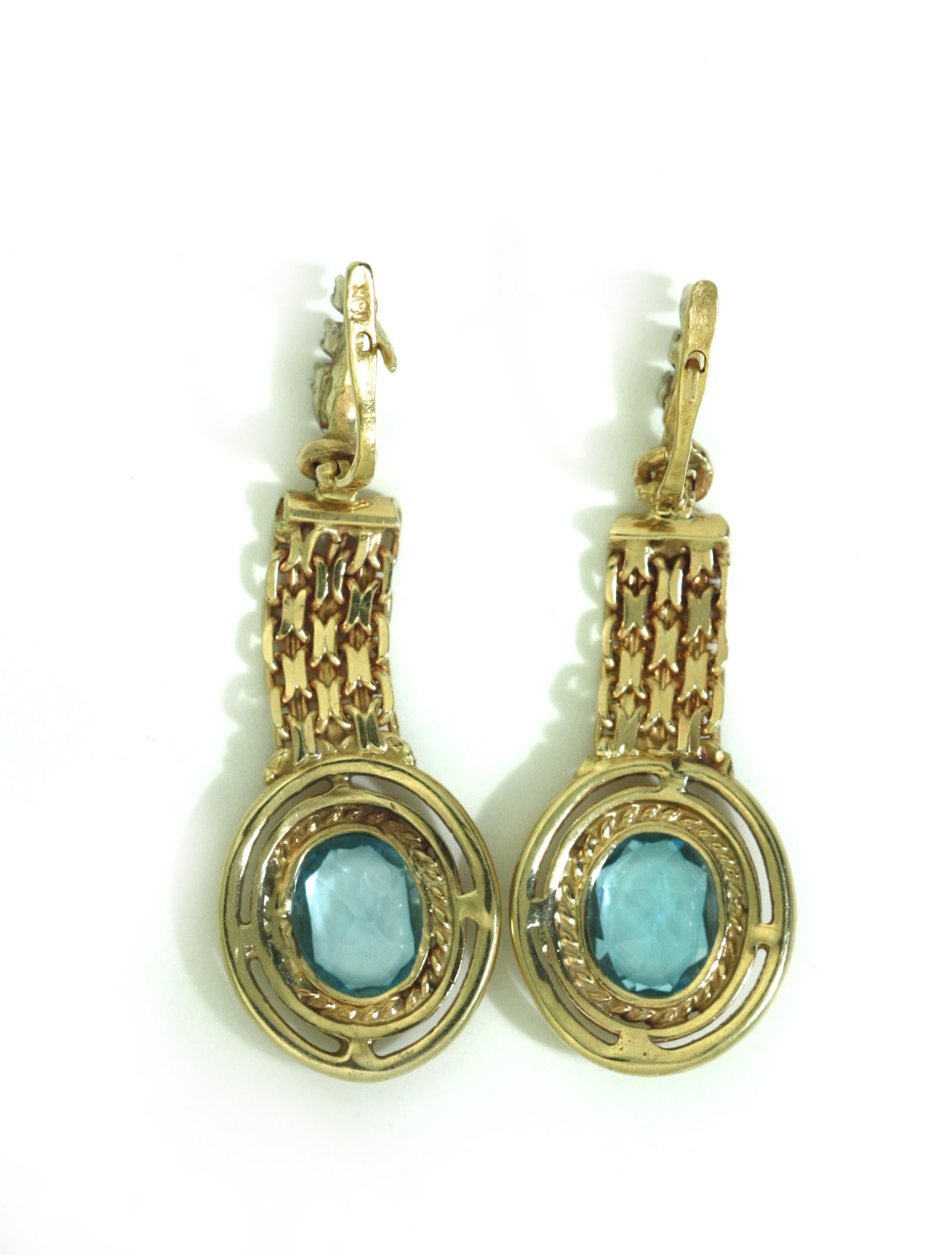 
Gold, Blue Topaz and Diamond Earrings
Each earring featuring a oval-shaped blue topaz to the center of a cluster of round brilliant-cut diamonds suspended by a diamond-set loop.
Diamonds weighing approximately 0.40 carats
Two Blue topaz weighing a