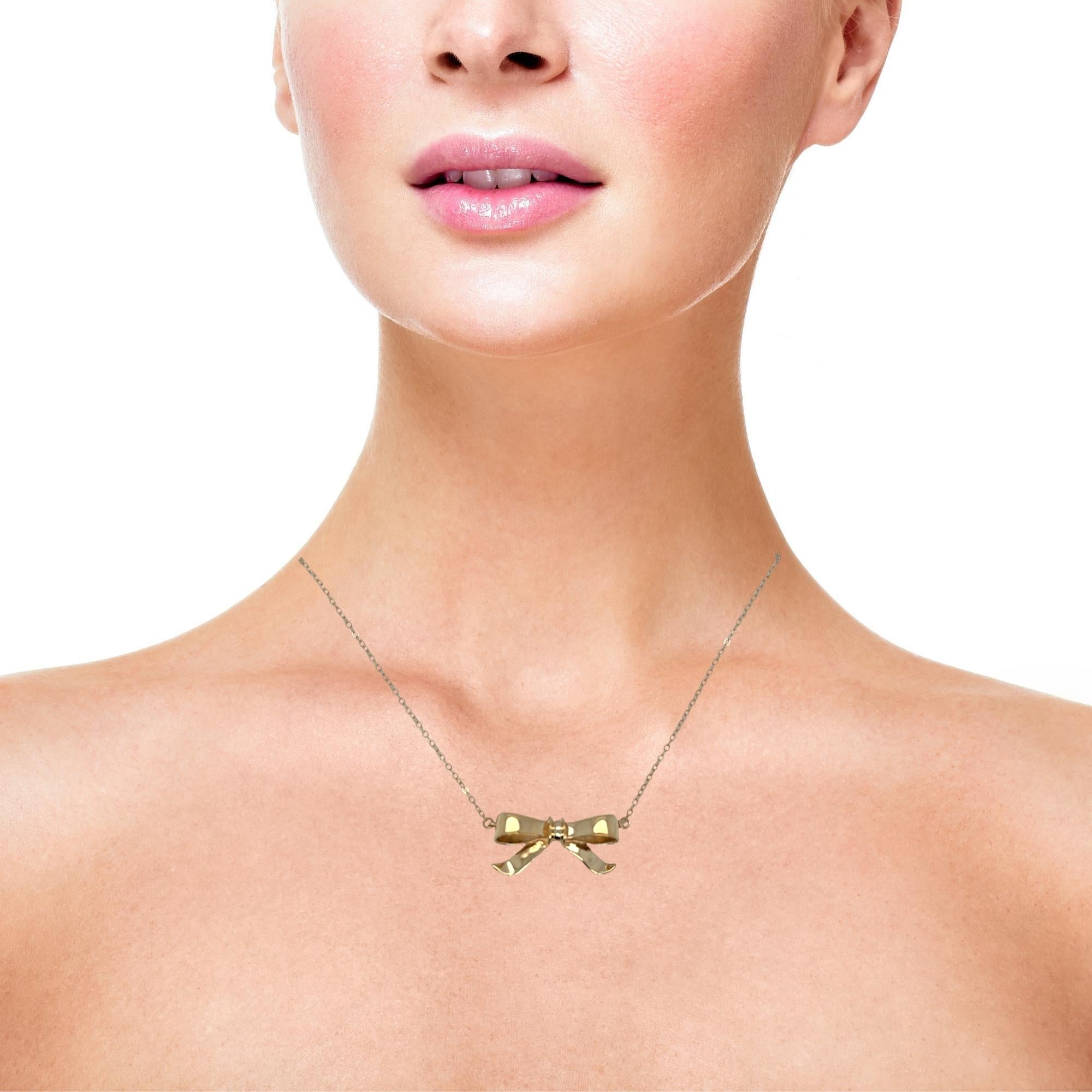 Dolce e raffinata, questa collana con fiocco in oro aggiunge un tocco di giocosa femminilità a qualsiasi look. Realizzato in oro giallo massiccio 14 carati, il fiocco è posizionato e collegato senza soluzione di continuità alla catena e si trova al
