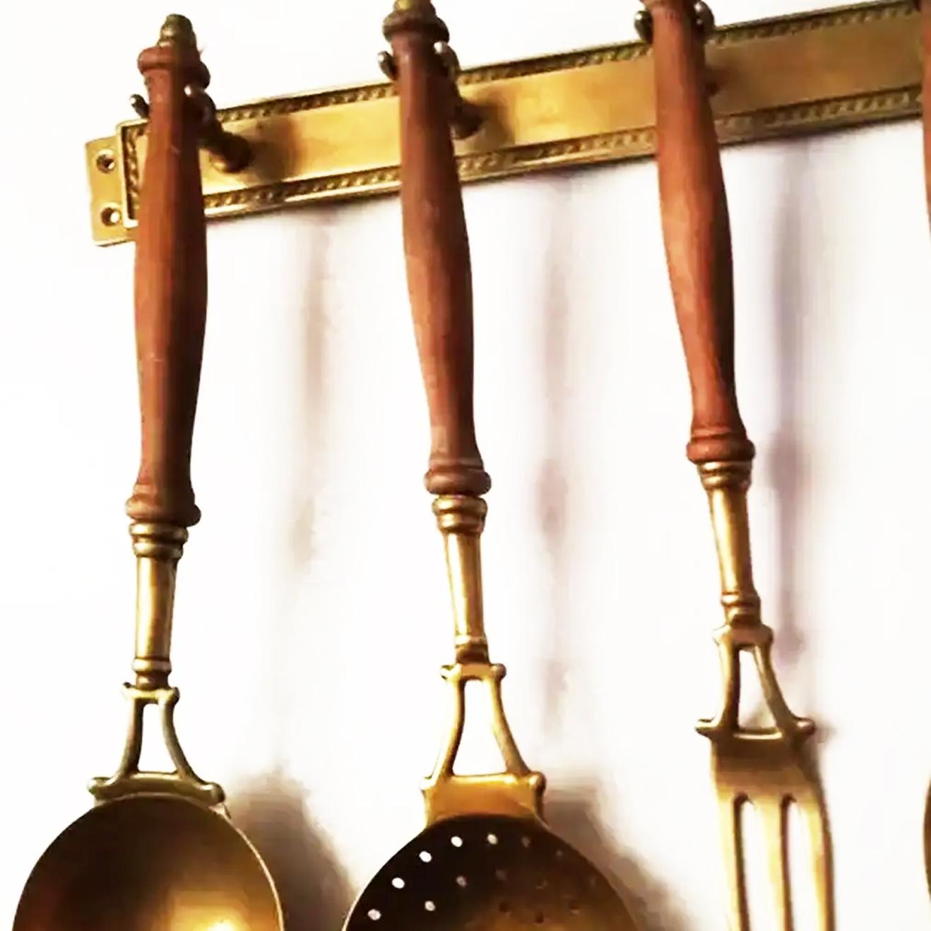 Old kitchen tools or utensils made of brass and wood hanging from a hanging bar. Old kitchen appliances,

Early 20th century

Saucepan fork palette and serving pot

This set of brass utensils is ideal to decorate a kitchen of any style, not