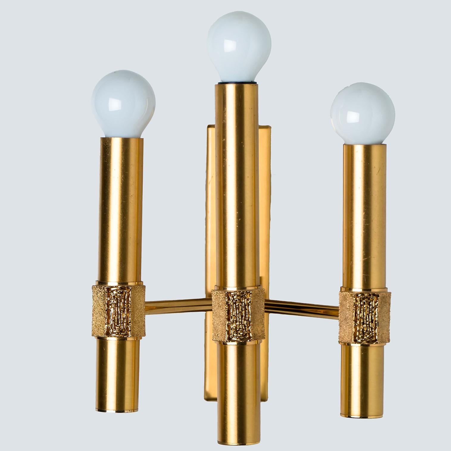 Beautiful wall light by Angelo Brotto, brass structure with 3 arms. The light consists of 3 brass arms, each with a light bulb on top. Each brass arm has a small structured piece on the front, to create a classy finish.

Dimensions:
Height: 11.81