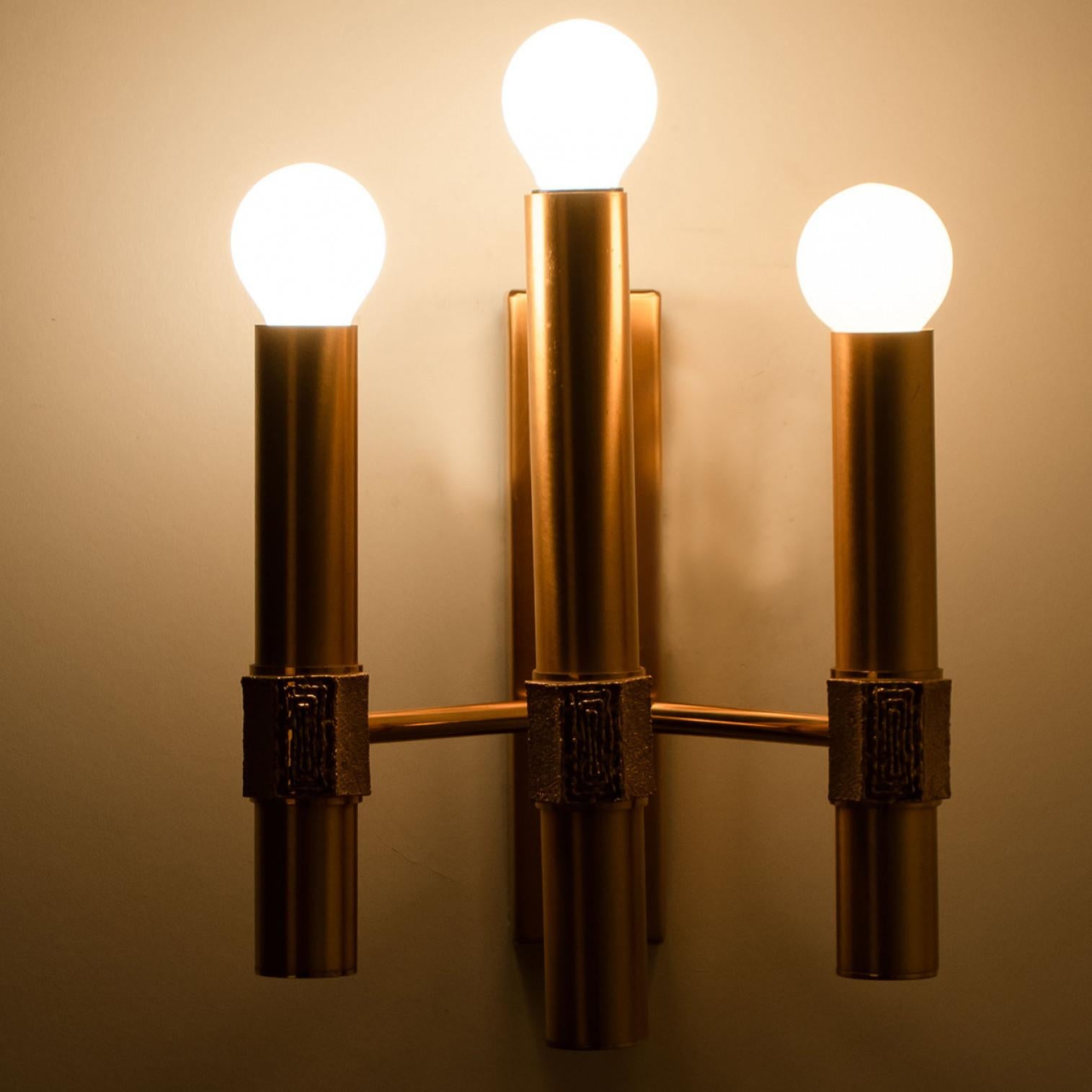 Beautiful wall light by Angelo Brotto, brass structure with 3 arms. The light consists of 3 brass arms, each with a light bulb on top. Each brass arm has a small structured piece on the front, to create a classy finish.

Dimensions:
Height: 11.81