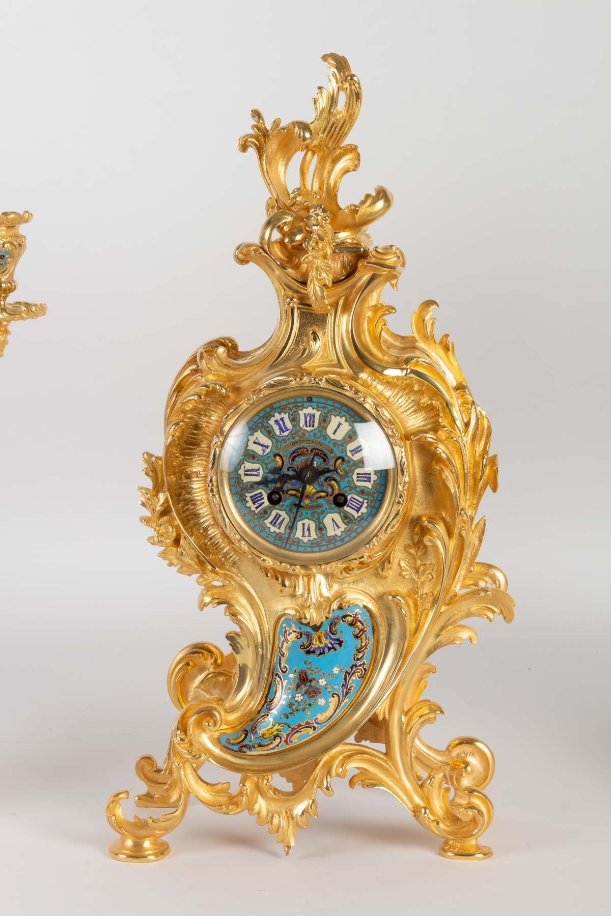 Gilded bronze and enamel mantel set.
Louis XV style, late 19th century. Napoleon III period
Measures: Clock H 49 cm, W 25cm, D 13cm
Candelabra H 58 cm , D 30 cm.
   
