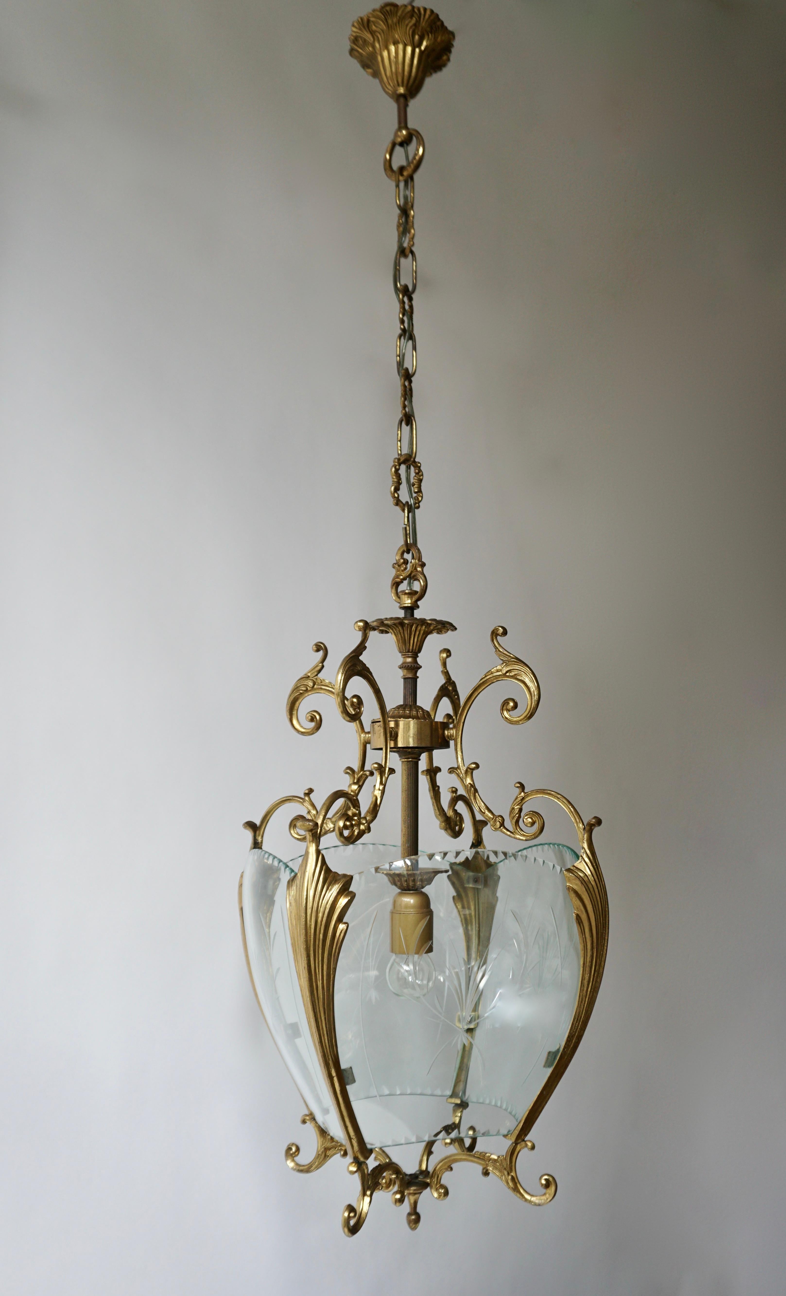 A superb and elegant gilt bronze lantern with curved glass panels.
France, circa 1930s-1950s.

Measures: Width 30 cm.
Depth 30 cm.
Height fixture 60 cm.
Total height with the chain 115 cm.
One E27 bulb.