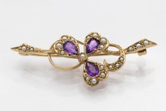 Gold brooch in the shape of a clover with amethysts and pearls.