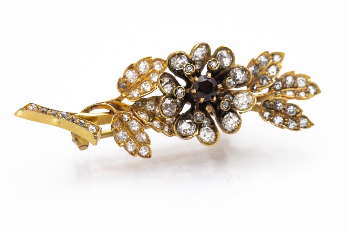 Flower shaped brooch with a round-cut garnet weighing approx. 0.40ct, surrounded by 76 diamonds in old brilliant cuts with a total weight of 2.40ct.
Brooch set in 18-karat gold. 
Comfortable and secure clasp.
Origin: Western Europe, mid-20th