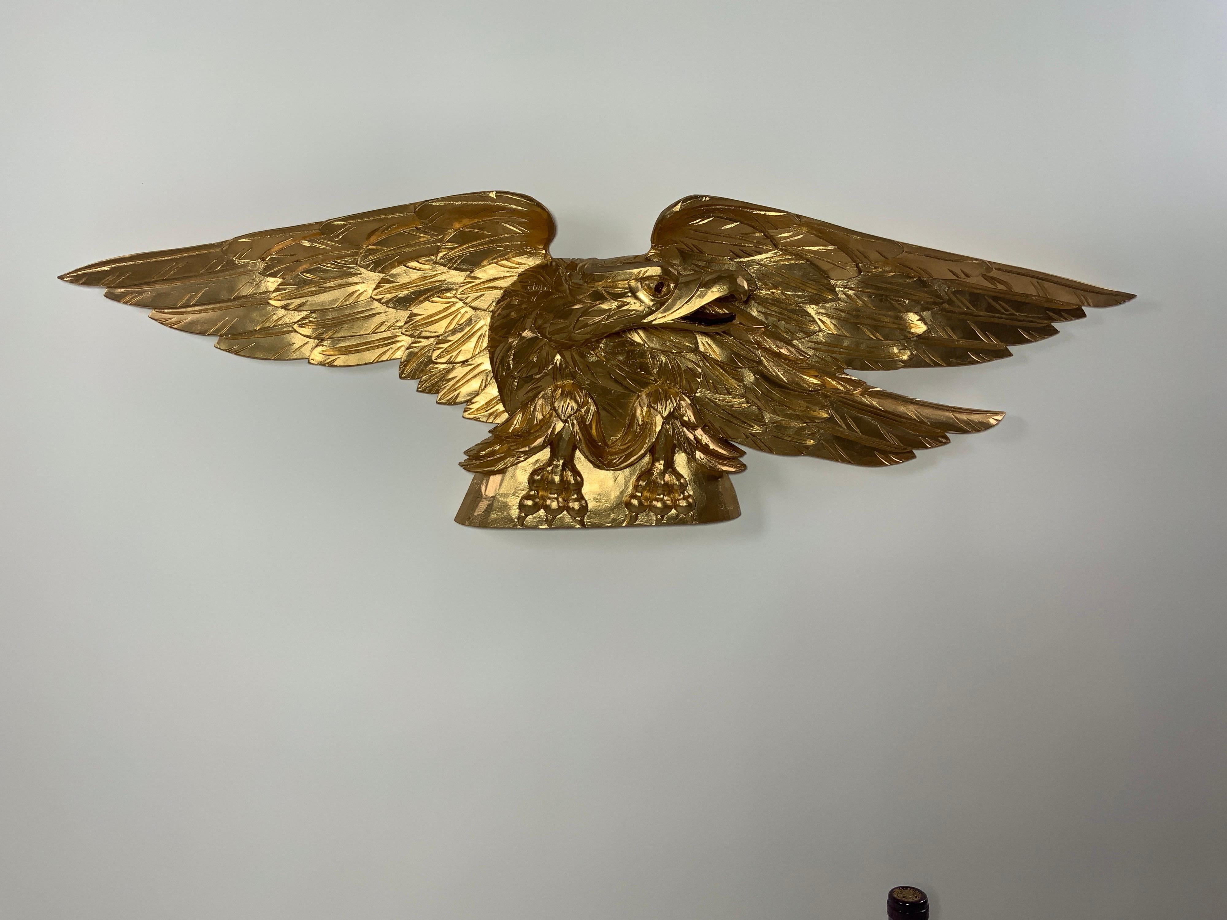 Carved eagle with pediment base. Heavily carved wings. Expertly executed. Flat bottom. Can be displayed on a mantle, over a door, or hung. Gold painted painted finish.

Overall dimensions: 11