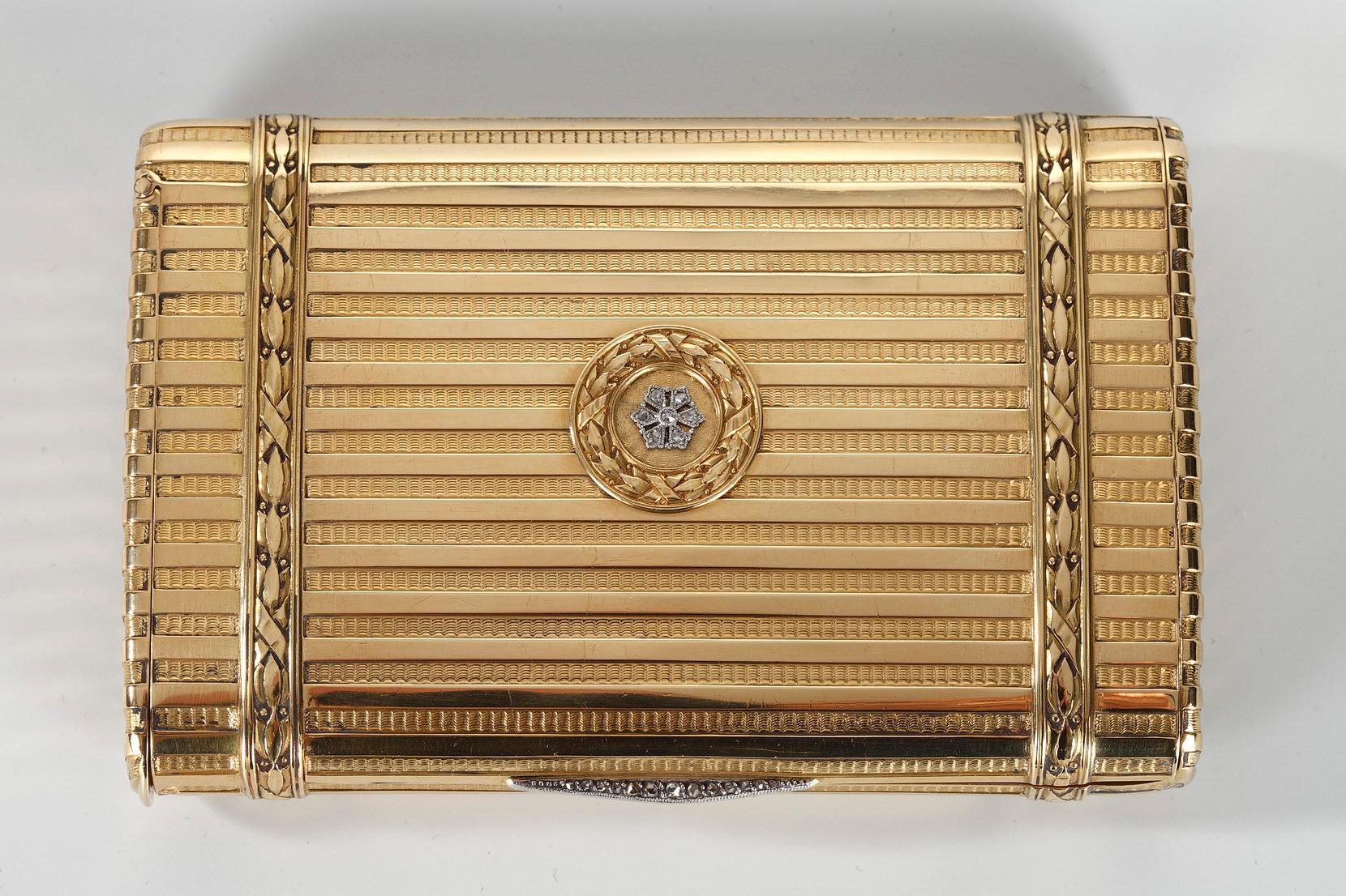 Large and large rectangular shaped gold case. The case is decorated with a fine decor of case is embellished with intricate geometric patterns of parallel stripes alternating with bands of polished gold. The hinged lid is decorated with a rosette