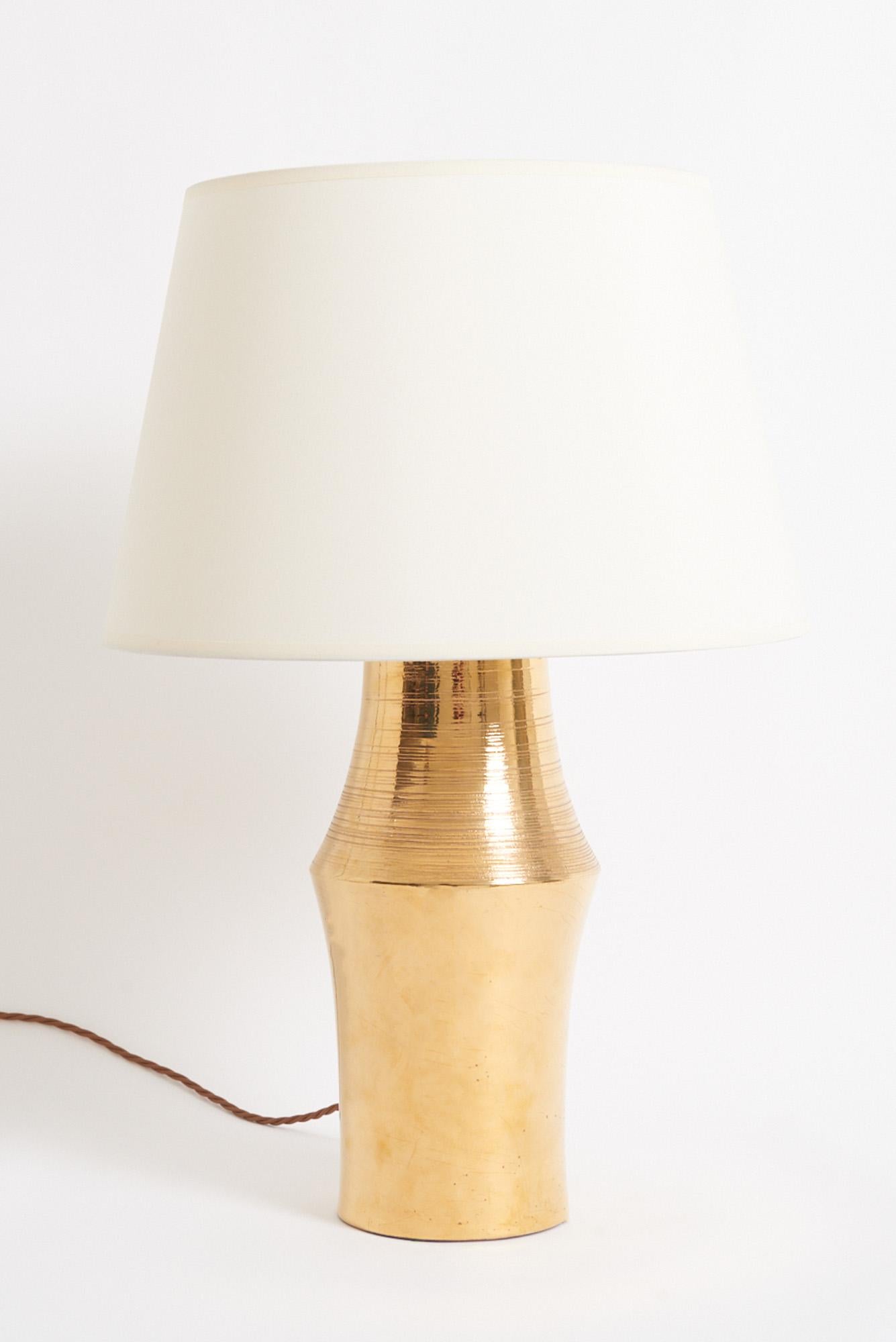 Lampe de table en céramique à glaçure dorée, fabriquée par Bitossi Italie pour Miranda AB en Suède, années 1970.
Avec l'abat-jour : 59 cm de haut par 41 cm de diamètre 
Base de la lampe uniquement : 41 cm de haut par 19 cm de diamètre