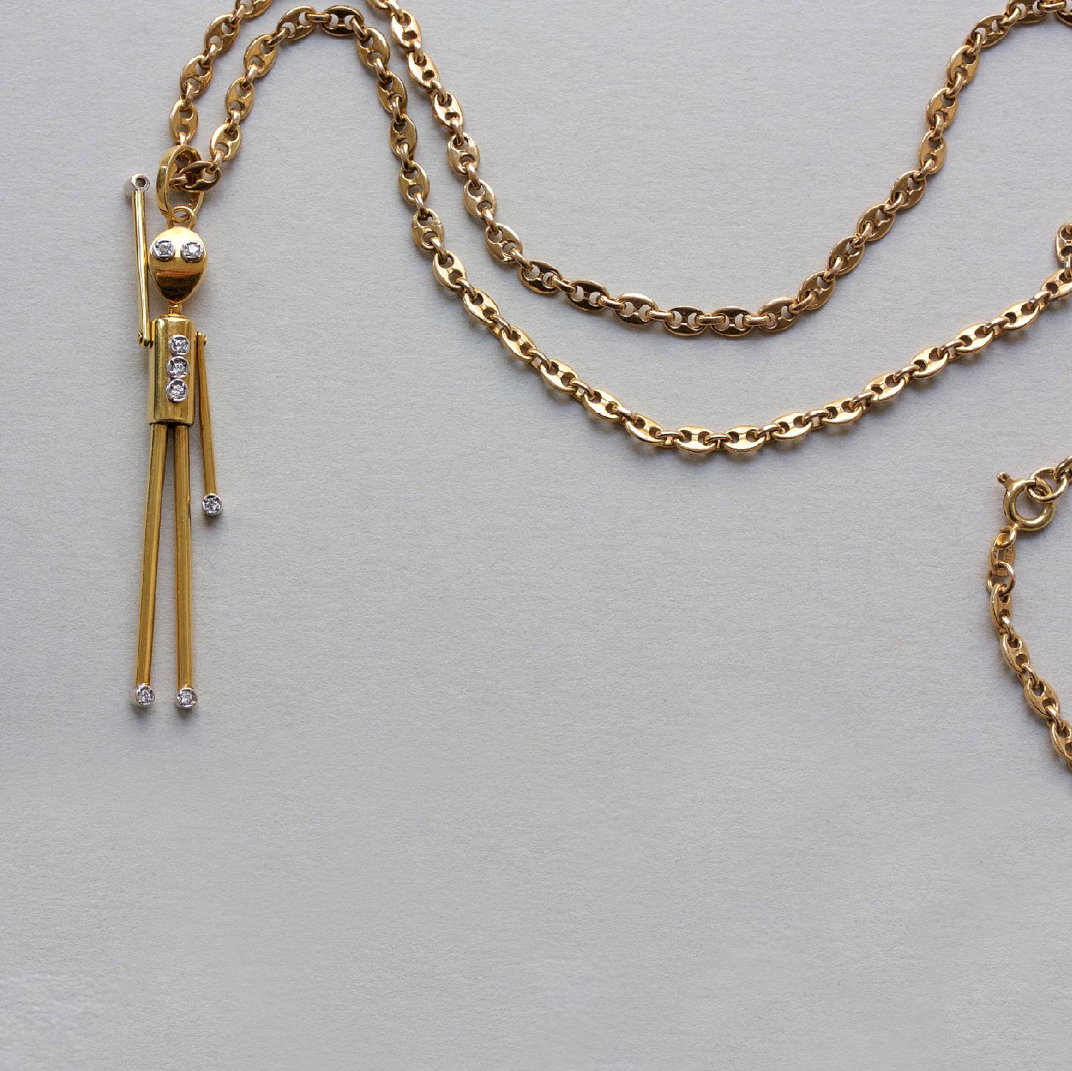 A 14 carat gold articulate stick man or robit charm with diamond eyes, hands, feet and buttons on a 14 carat gold mariner link chain, Italy, circa 1975.

weight: 20.08 grams
length chain: 61 cm
dimensions charm: 6 x 1 cm