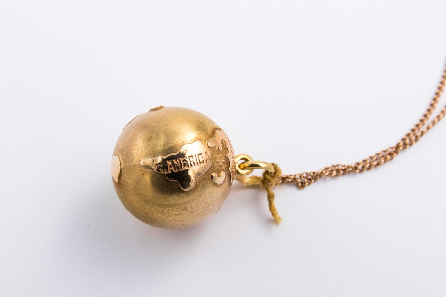 Circa mid-20th century gold charm necklace consisting of an 18 karat gold globe paired with an Italian black horn amulet. Charms are strung on an 18 karat gold chain. The globe charm also features labels of each country.
