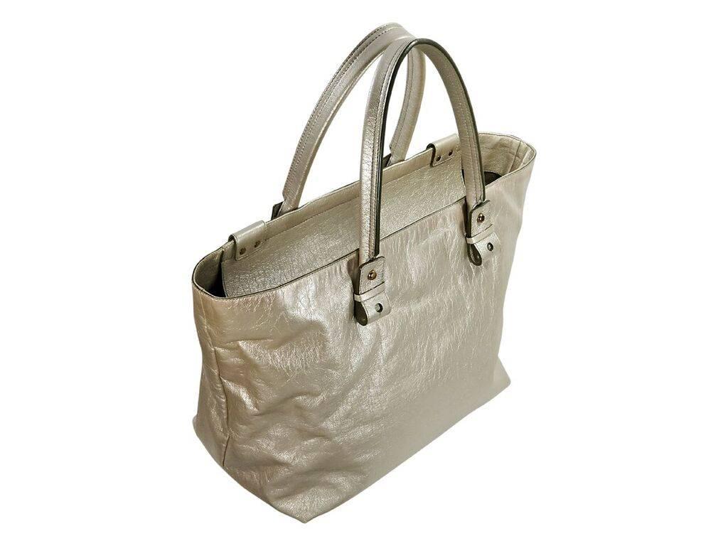 Product details:  Gold leather tote bag by Chloe.  Logo design accents front.  Dual shoulder straps.  Top zip closure.  Lined interior with inner slide pocket.  Front exterior zip pockets.  Silvertone and goldtone hardware.  18