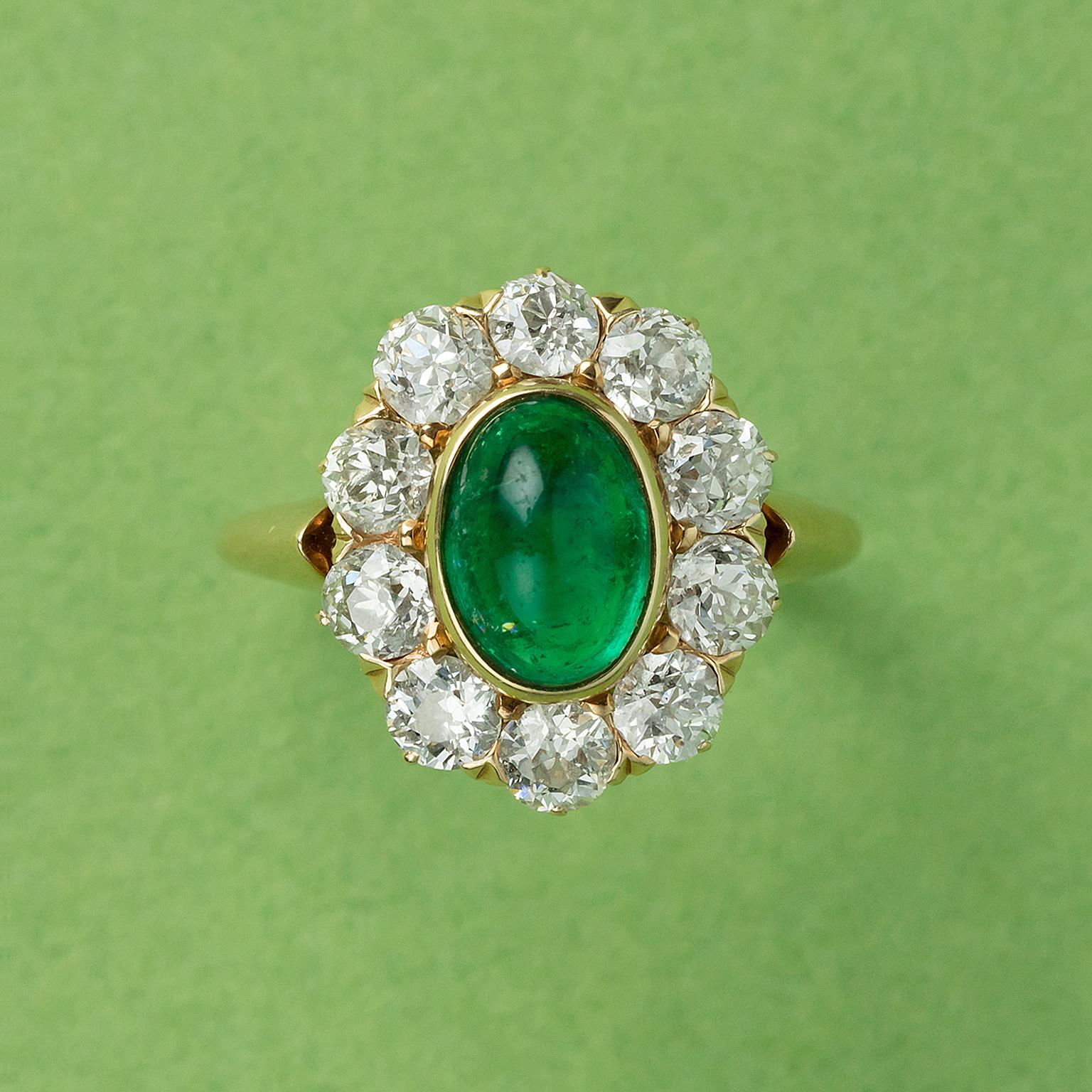 An 18 carat yellow gold cluster ring bezel set oval cabochon cut emerald (1.54 carat, Colombian minor) with ten old cut diamonds surround (circa 1.5 carat), American, circa 1910.

weight: 9.30 grams
ring  size: 17+ mm / 6 ¾ US.
width: 1.2 – 16 mm