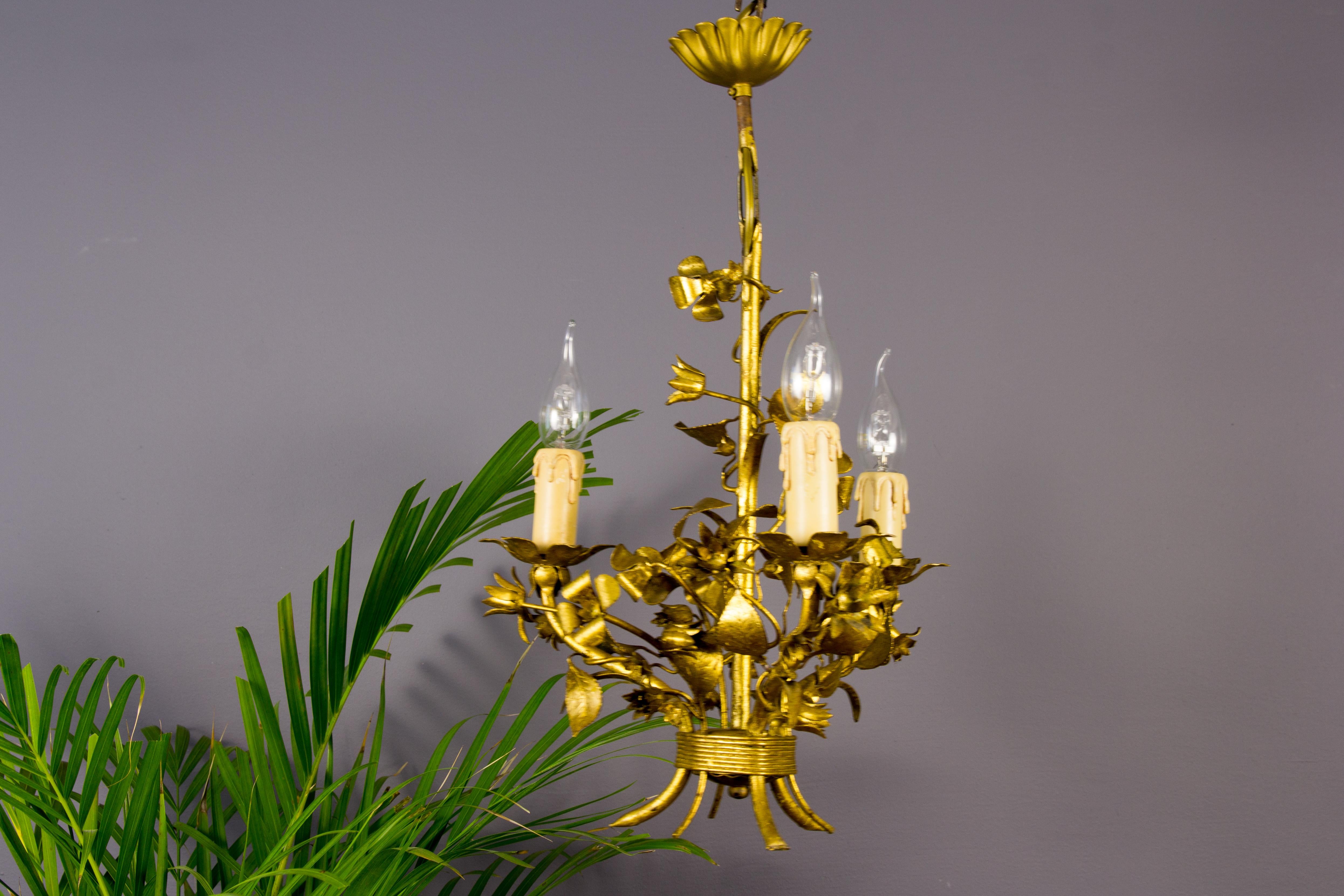 A tole chandelier produced in Italy in the 1950s. Finely made with gold-colored metal leaves and flowers, three arms with sockets for E 14 light bulbs. 
Dimensions:
Diameter: 32 cm / 12.59 in
Height: 52 cm / 20.47 in.