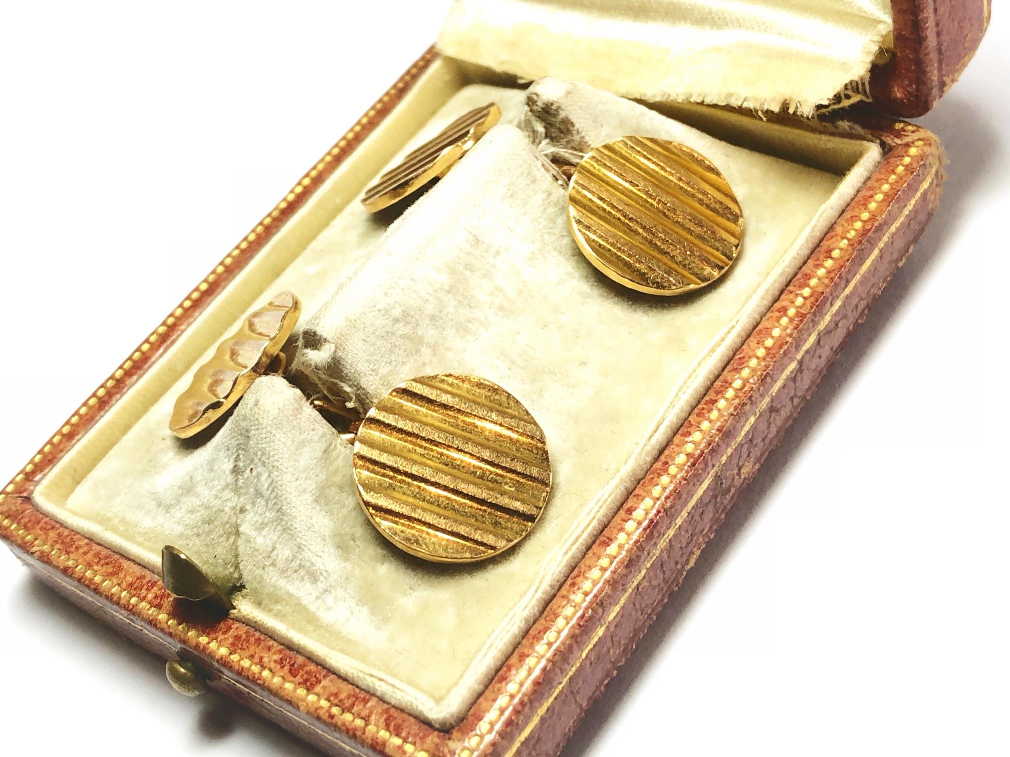 A pair of circular gold cufflinks, each link with a ribbed textured face, with chain link fittings, mounted in 18ct yellow gold, with French marks. Circa 1965.
