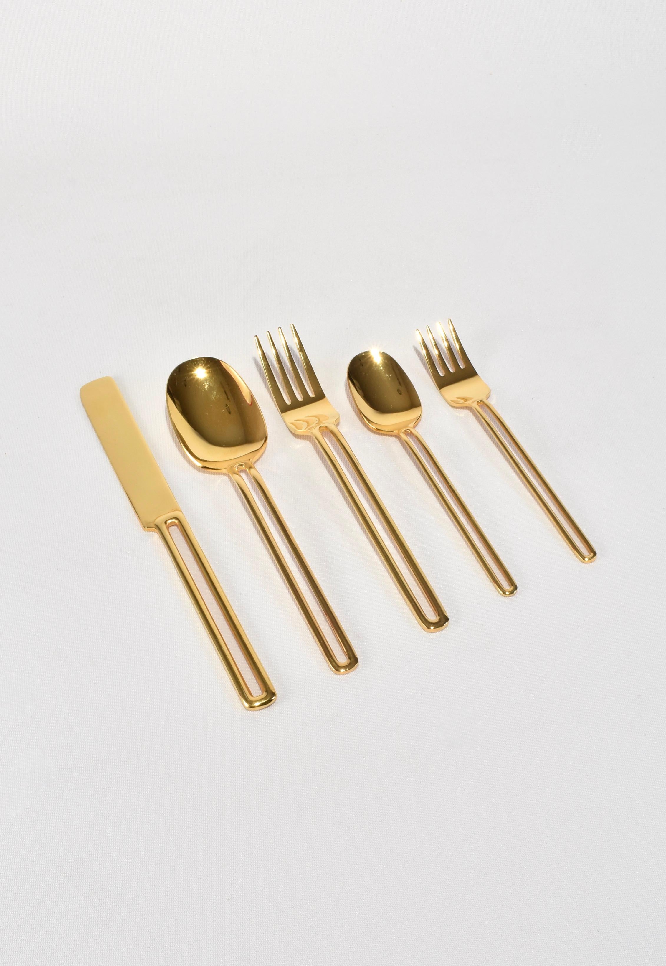 Rare, gold stainless steel five-piece flatware set with cutout handle. Stamped Oxford Hall, Stainless Japan.

Purchase includes one set of five pieces, eight sets available.

Dimensions: 
Knife: 9