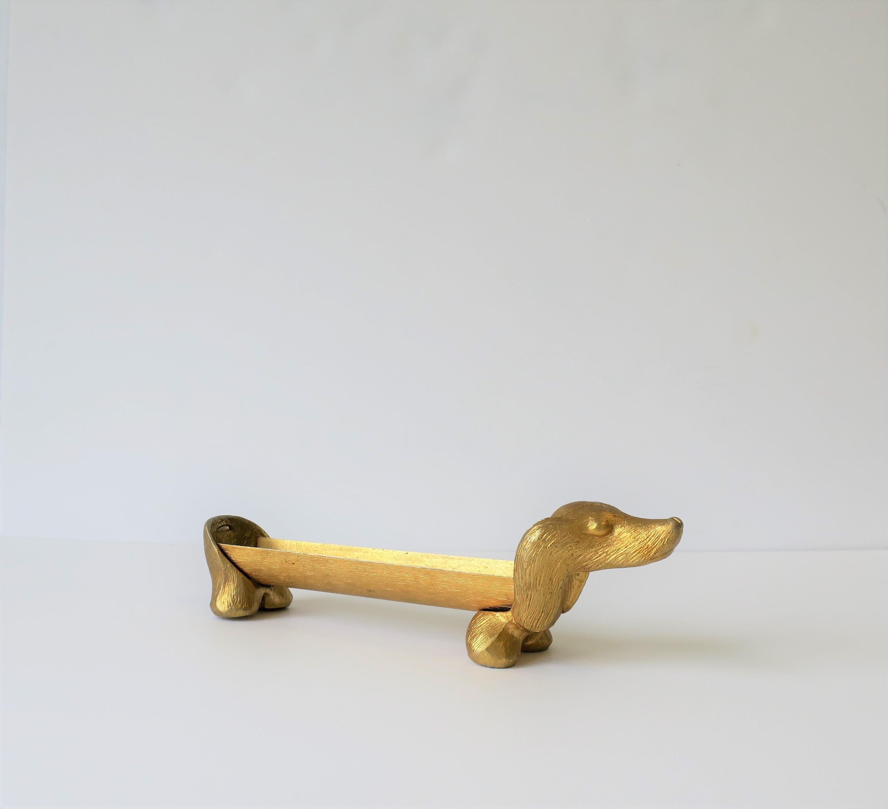 A vintage gold-tone Dachshund dog cracker or cookie holder, circa 1970s or a little later. Dachshund dog holds round cookies or crackers, e.g., 'Ritz' crackers. A great entertaining piece. 

Dog measures: 11.75