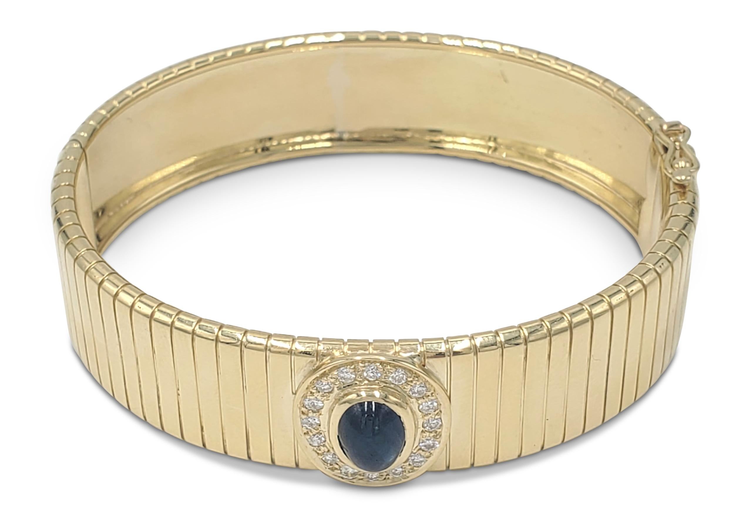 An 18 karat yellow gold bangle centering on one blue sapphire weighing an estimated 1.60 carats surrounded by round brilliant cut diamonds (0.16cttw). Signed Soler Cabot, Faberge. Bangle is not presented with original box or papers. 6 inches in