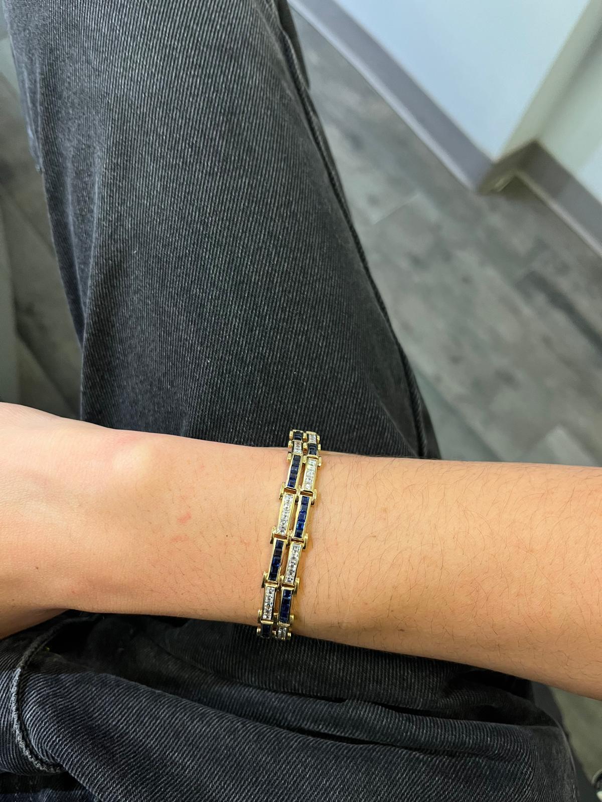 Un bracelet à maillons en or jaune 18 carats comprenant 70 diamants de taille carrée et 70 saphirs de taille carrée. Le bracelet est composé de 14 maillons, chaque maillon étant serti alternativement de diamants ou de saphirs. Les diamants sont de