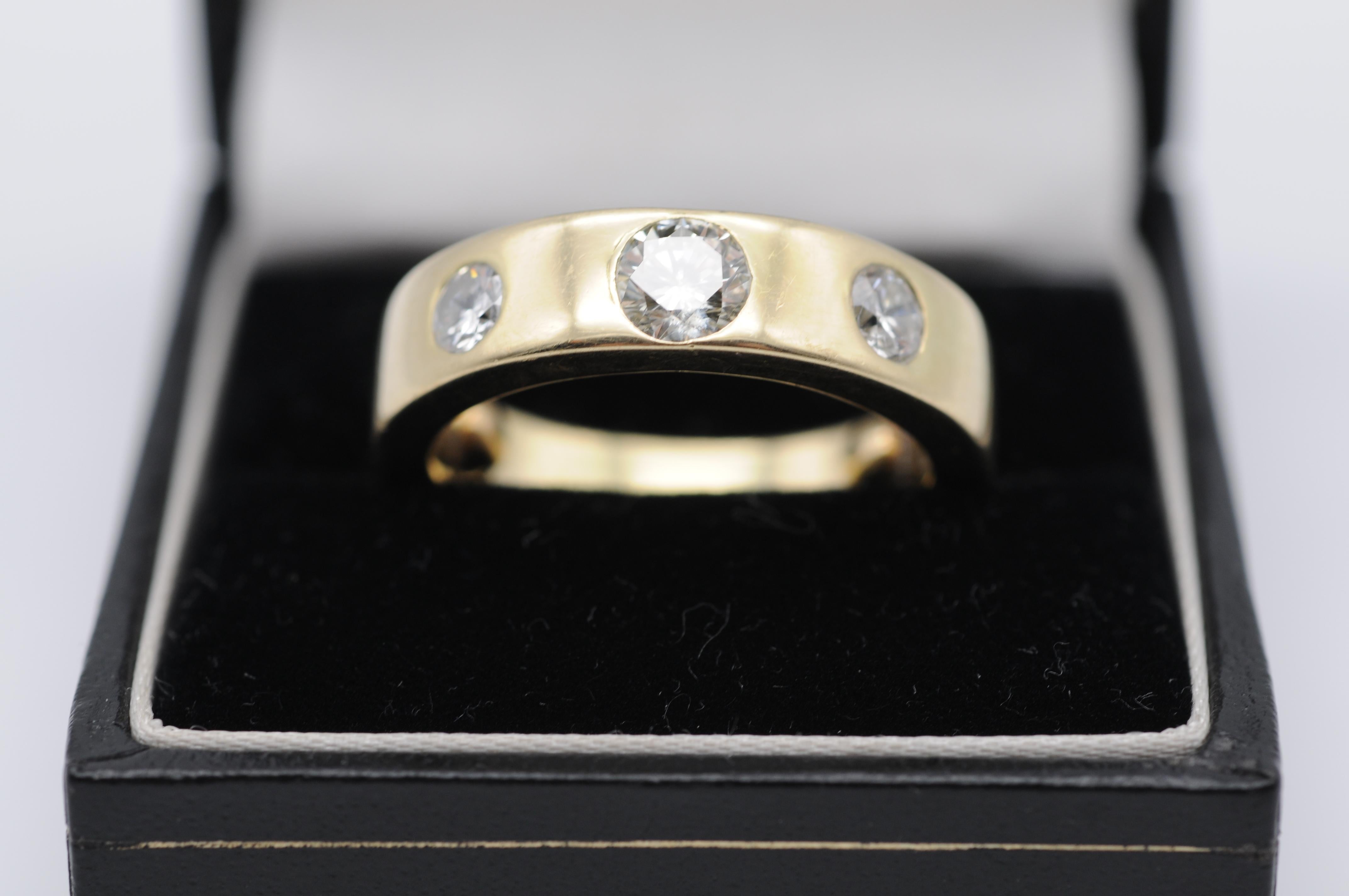 Treten Sie ein in die Welt der Raffinesse und Eleganz mit diesem Diamantring aus 14 Karat Gelbgold. Das klassische Design besteht aus drei exquisiten Diamanten, die jeden, der sie betrachtet, in ihren Bann ziehen.

Der zentrale Diamant ist ein